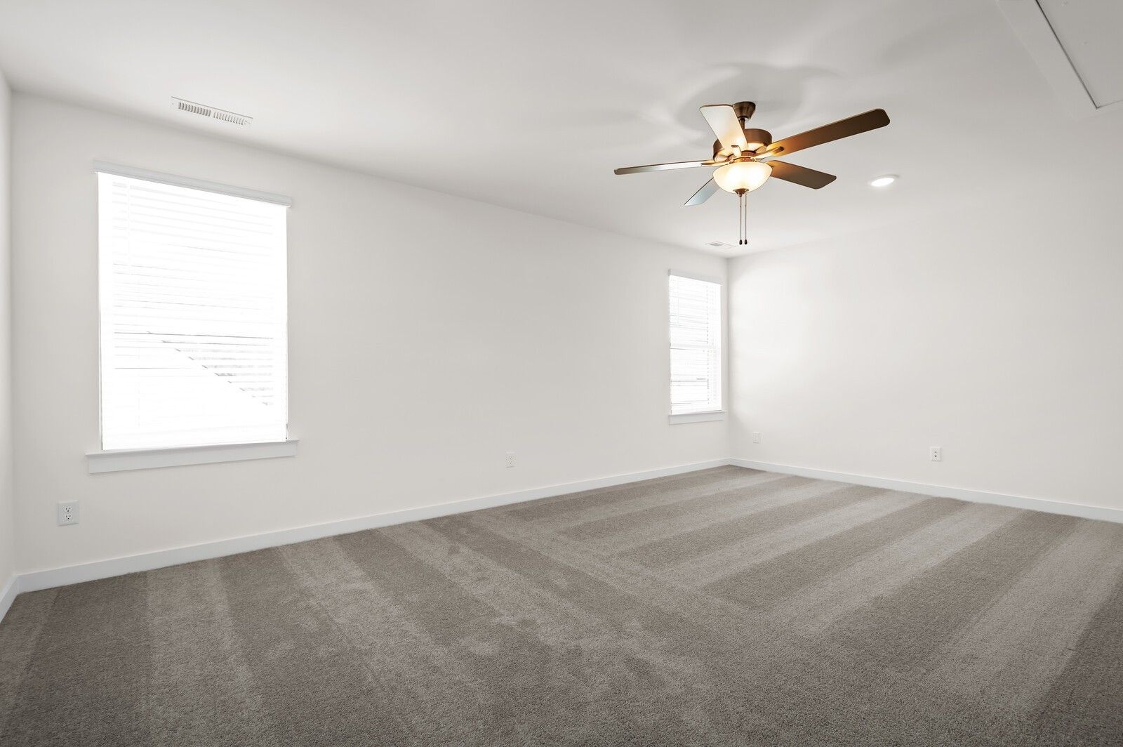 Spacious, carpeted bedroom with ceiling fan in The Ash A floor plan at Woods Crossing, Gallatin, Tennessee.