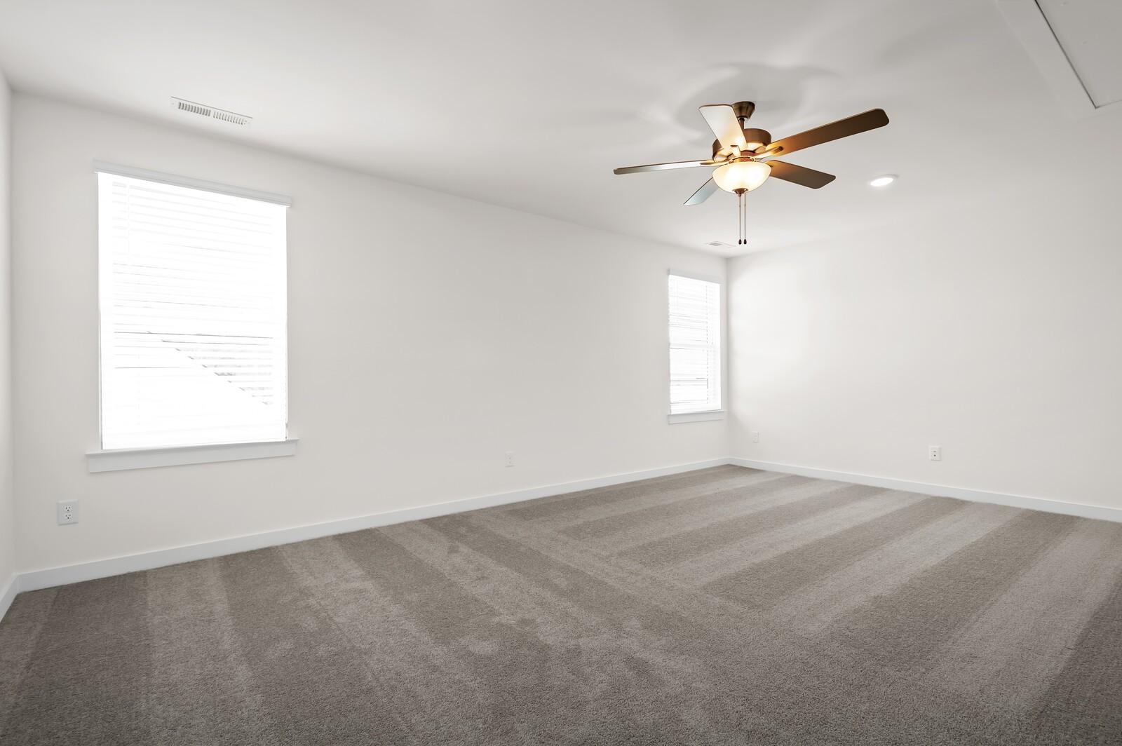 Spacious, carpeted bedroom with ceiling fan in The Ash A floor plan at Woods Crossing, Gallatin, Tennessee.