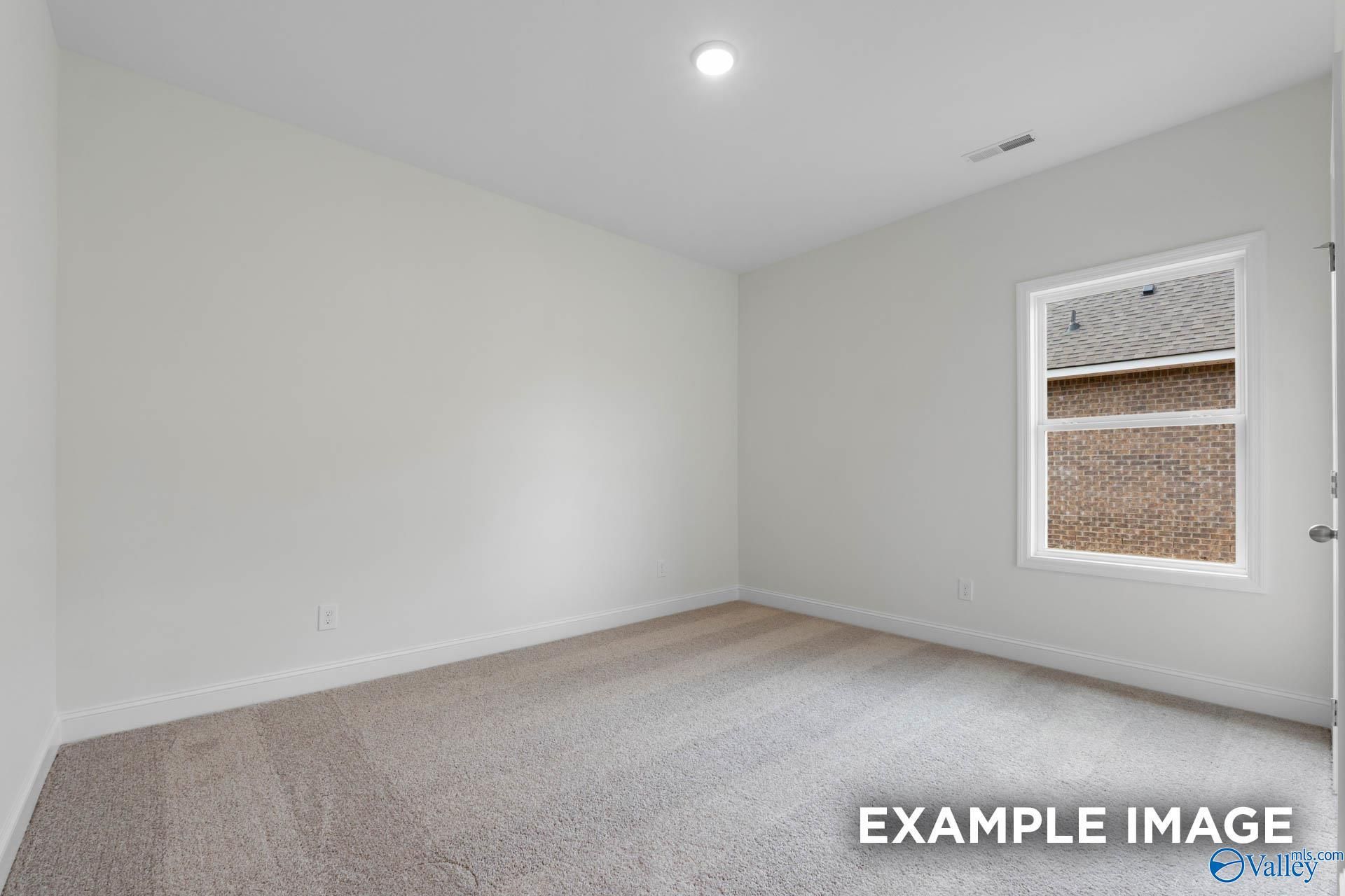 Bright secondary bedroom with neutral walls, plush carpet, and window in Evermore Homes Daphne E, Harvest, AL