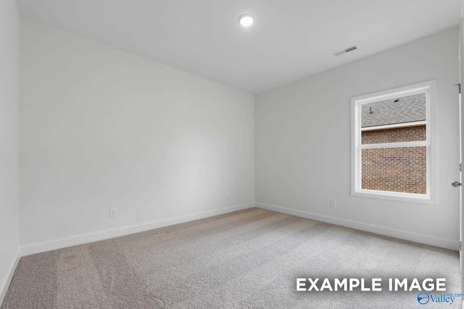 Bright secondary bedroom with neutral walls, carpeted floors, and window in Davidson Homes The Daphne D, Athens, Alabama