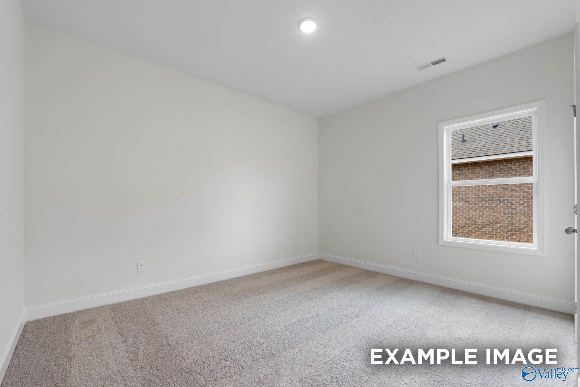 Bright secondary bedroom with neutral walls, plush carpet, and window in Evermore Homes Daphne E, Harvest, AL