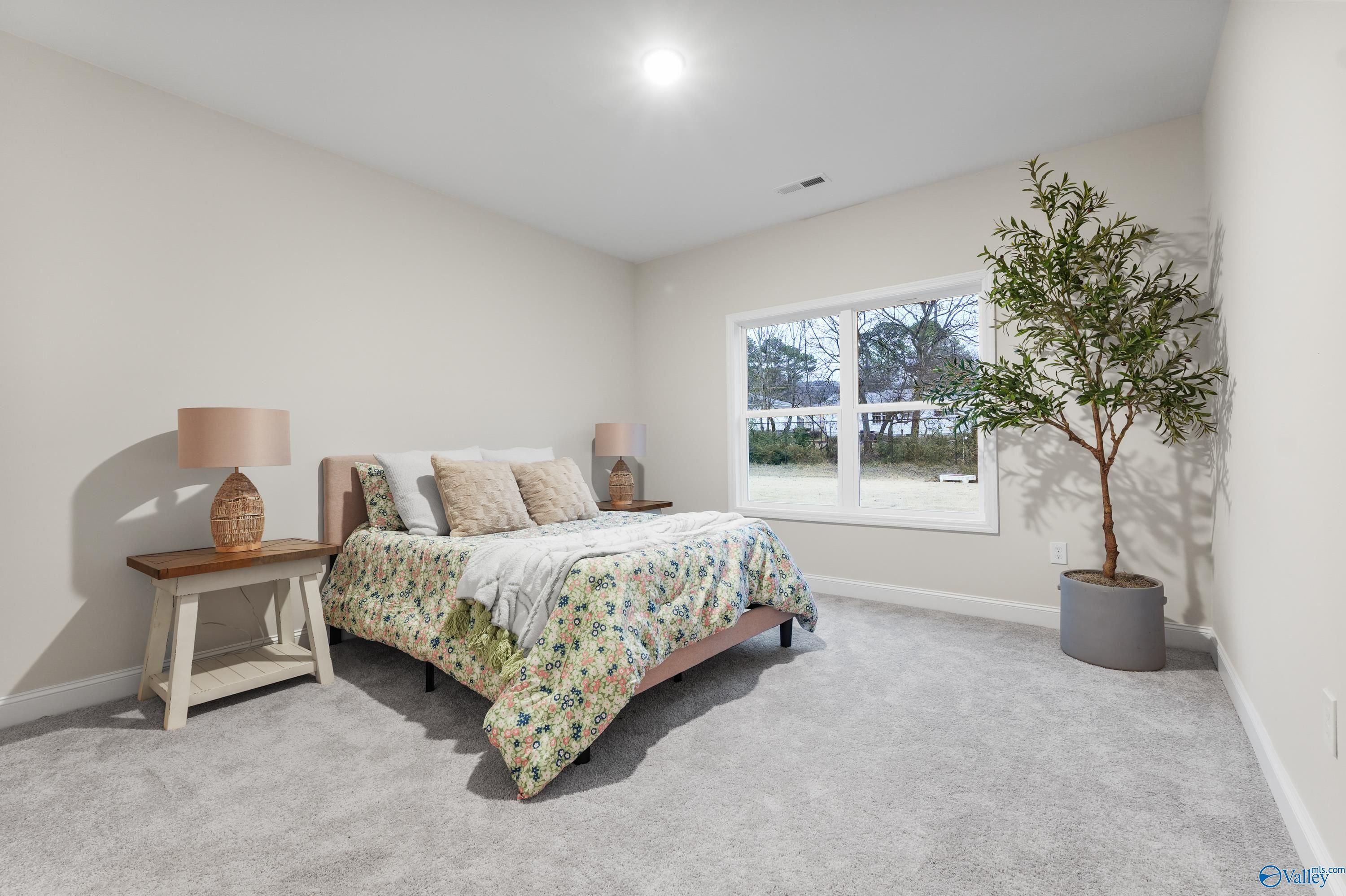 Cozy secondary bedroom with floral bedding, potted tree, and large window in Davidson Homes The Asheville C, Jaguar Hills, Huntsville AL