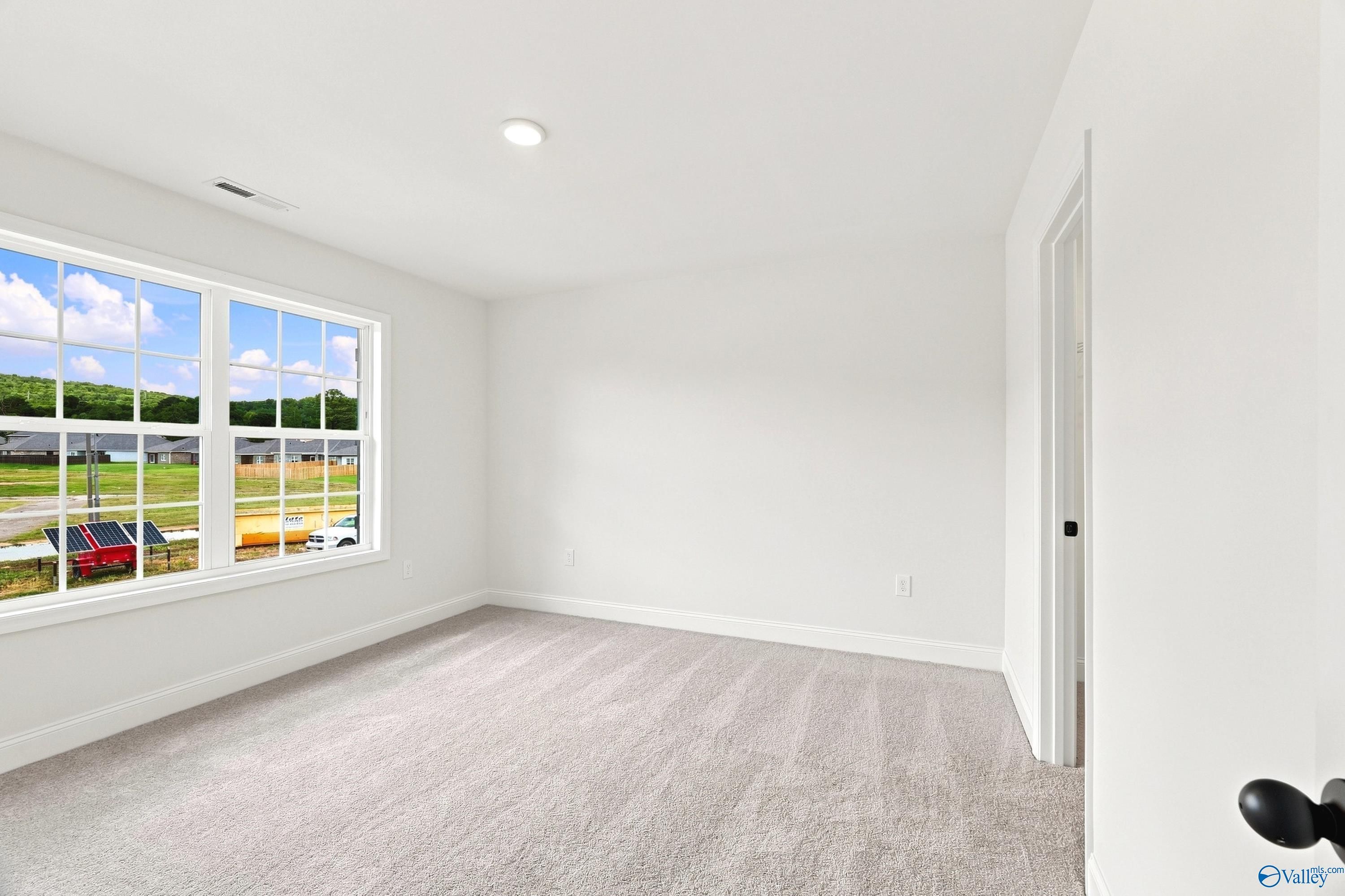 Bright bedroom with neutral carpet and large window in The Shelby B floor plan at Jaguar Hills, Huntsville, Alabama.