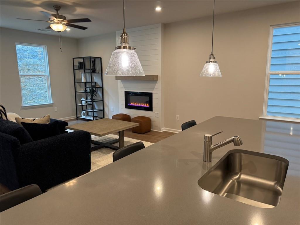 Open-concept living room with gas fireplace, pendant lights, and kitchen island sink in Davidson Homes The Cary A, Kennesaw, GA