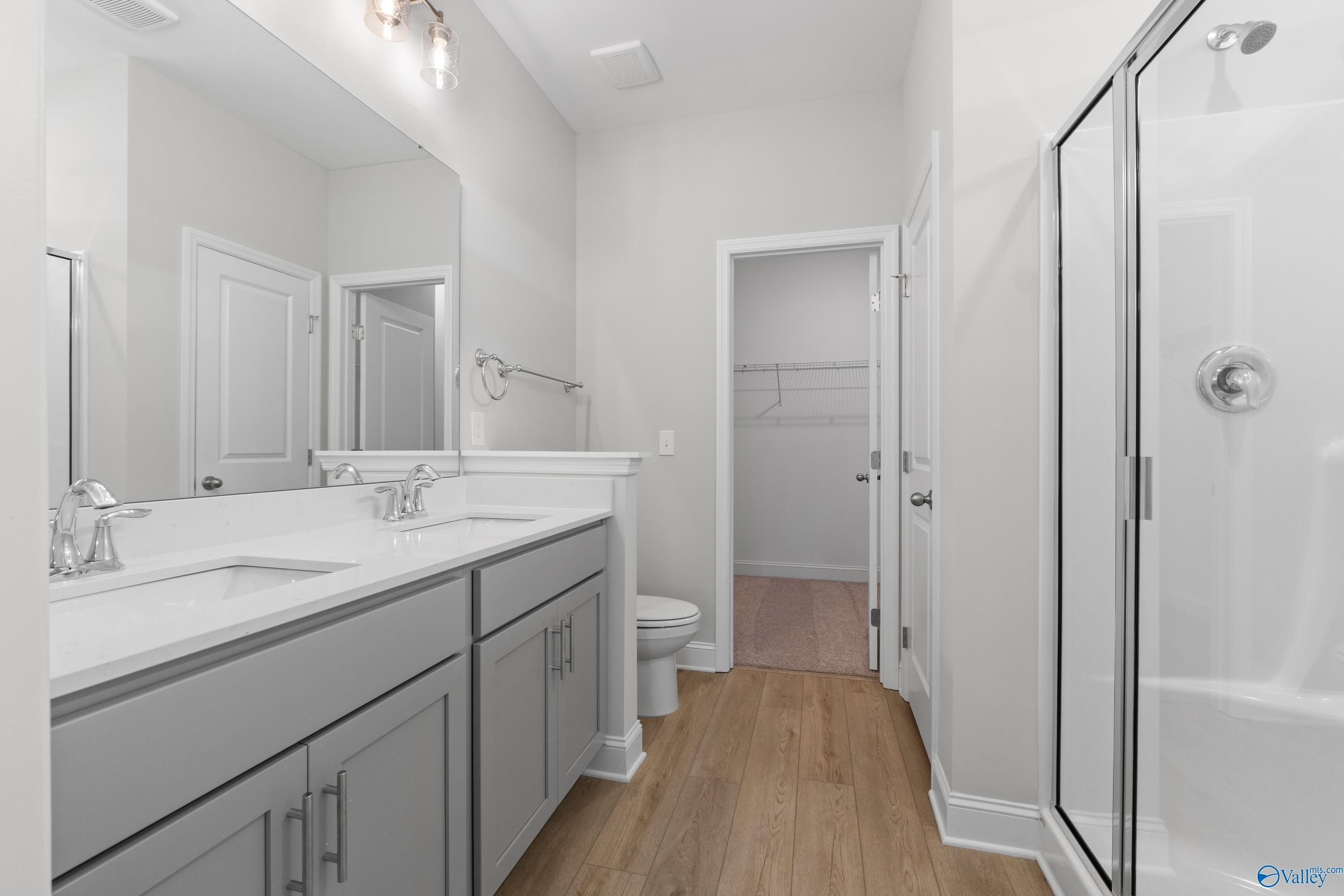 Modern master bathroom featuring double vanity, frameless glass shower, and walk-in closet in The Asheville by Davidson Homes, Huntsville, AL