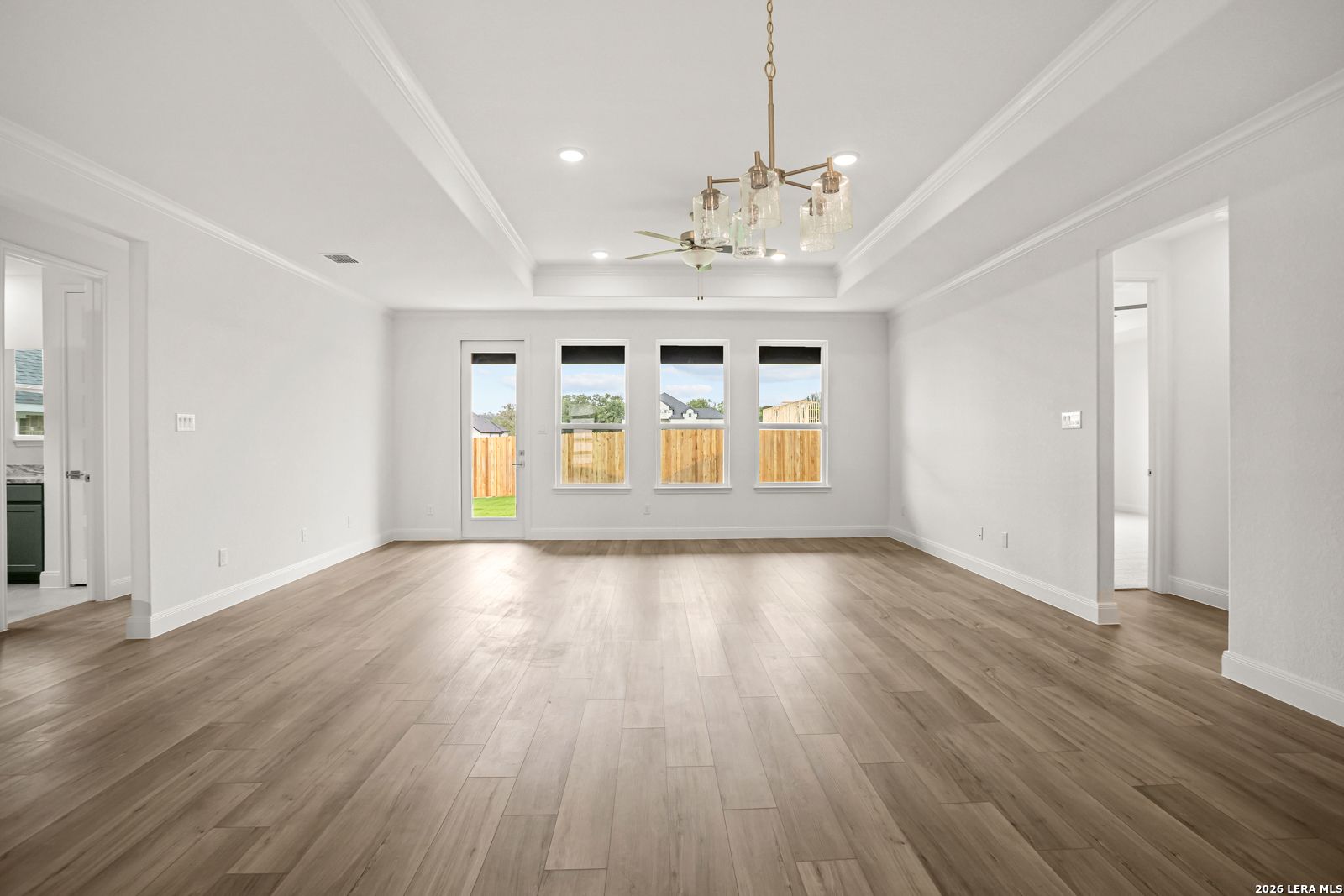 Spacious living room with tray ceiling and wood-look flooring in The Lanier G floor plan at The Reserve at Potranco Oaks.