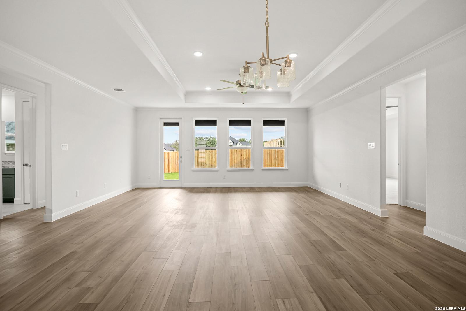 Spacious living room with tray ceiling and wood-look flooring in The Lanier G floor plan at The Reserve at Potranco Oaks.