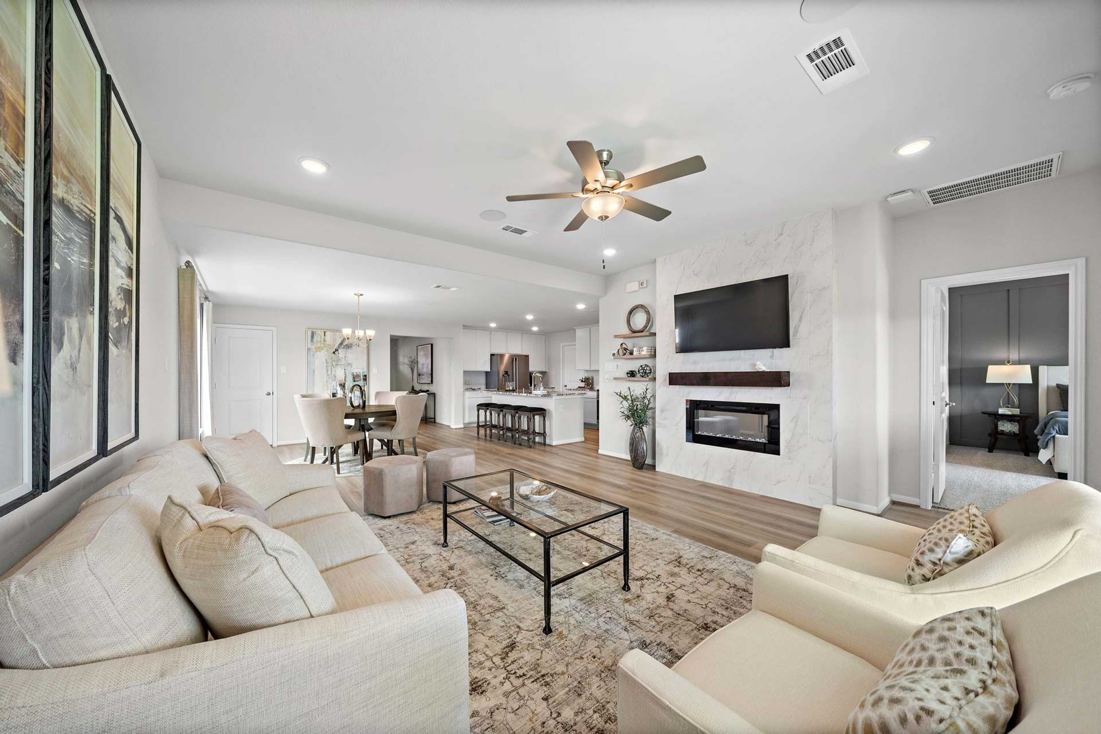 Spacious open-concept living room at Enclave at Newport in Crosby Texas by Davidson Homes featuring beige sofa fireplace and hardwood floors