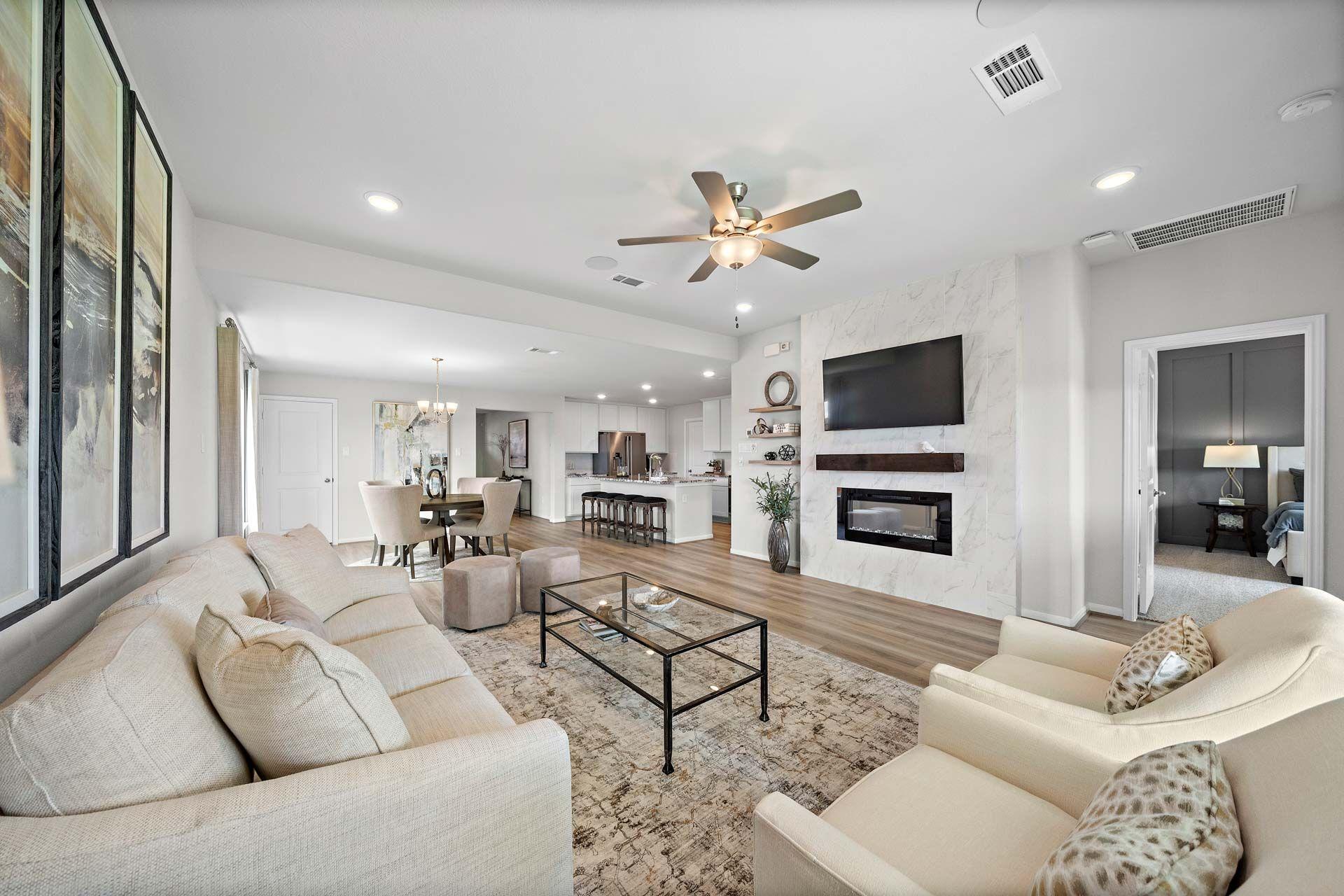 Spacious open-concept living room at Enclave at Newport in Crosby Texas by Davidson Homes featuring beige sofa fireplace and hardwood floors