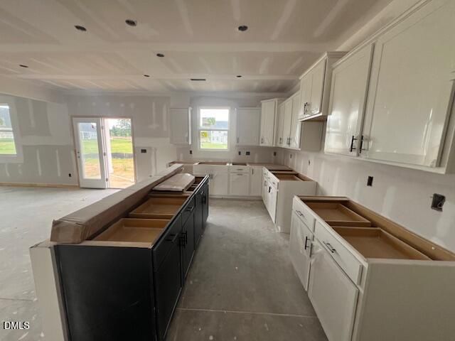 Unfinished kitchen with white cabinets and center island in The Hickory II C home at Retreat at North Main in Lillington.