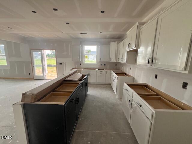 Unfinished kitchen with white cabinets and center island in The Hickory II C home at Retreat at North Main in Lillington.