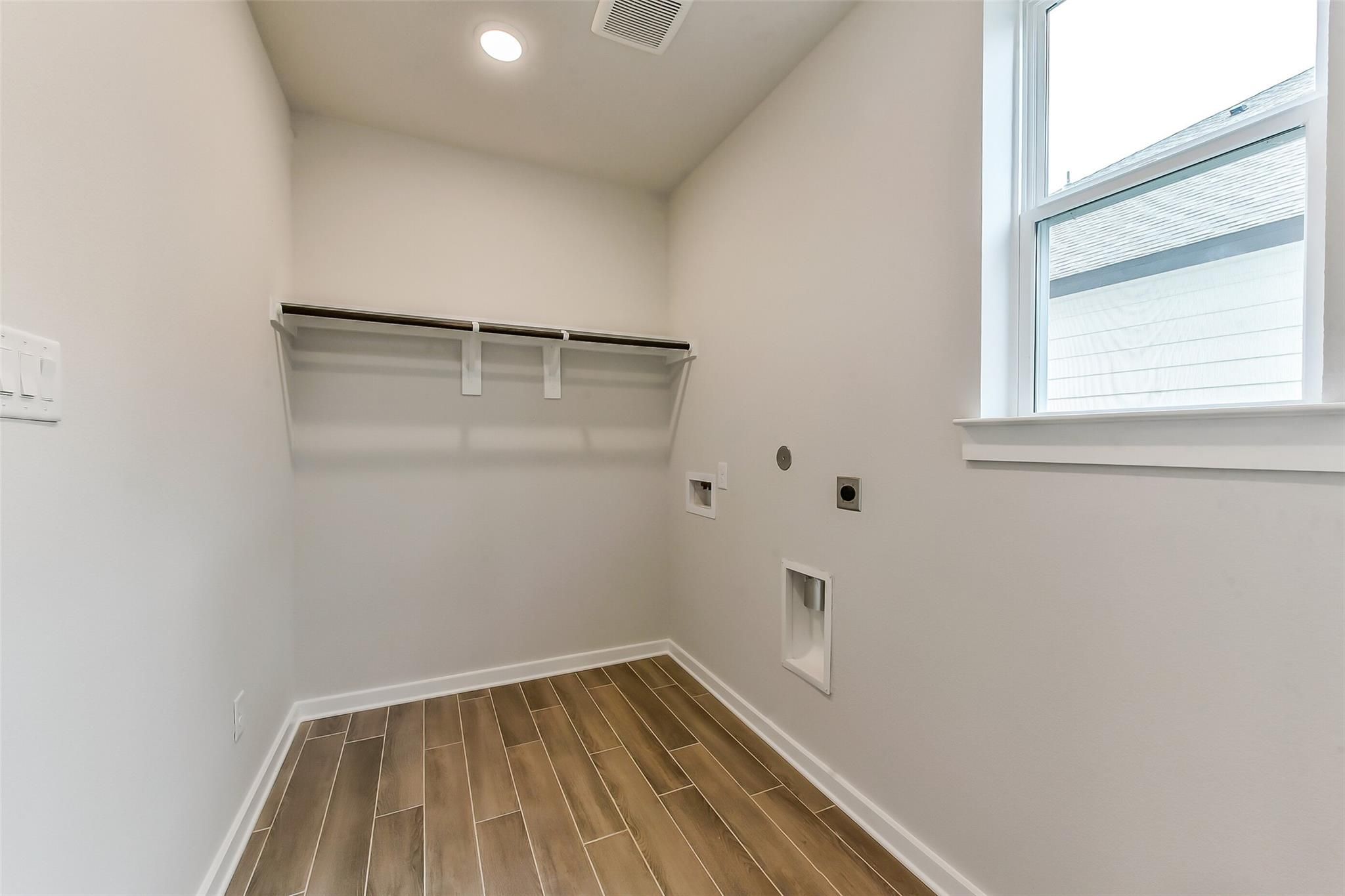 Modern laundry room with built-in shelves, washer-dryer hookups, wood-look tile floor in Davidson Homes Sequoia C, Crosby TX