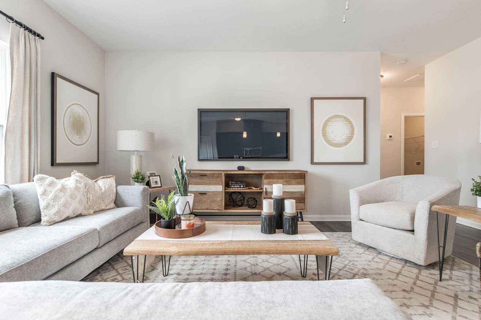 Spacious living room at Cape Reserve at Donahue Ridge in Auburn AL with gray sectional sofa, wooden coffee table, mounted TV, abstract art