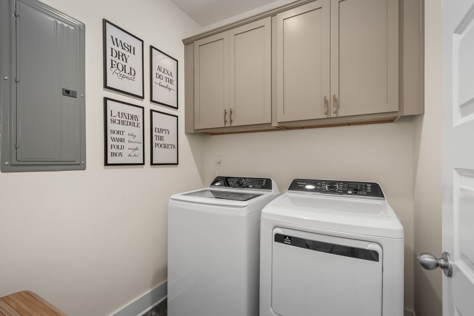 Spacious laundry room in The Ridgeport E with white washer dryer, shaker cabinets, folding counter, and motivational wall art