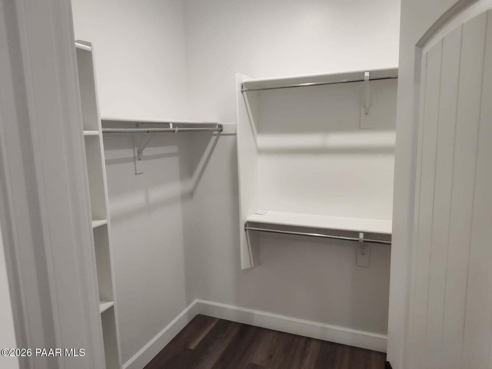 Spacious walk-in closet with white shelving, double hanging rods, and luxury vinyl plank flooring in Davidson Homes The Harmony C, Prescott Valley, AZ