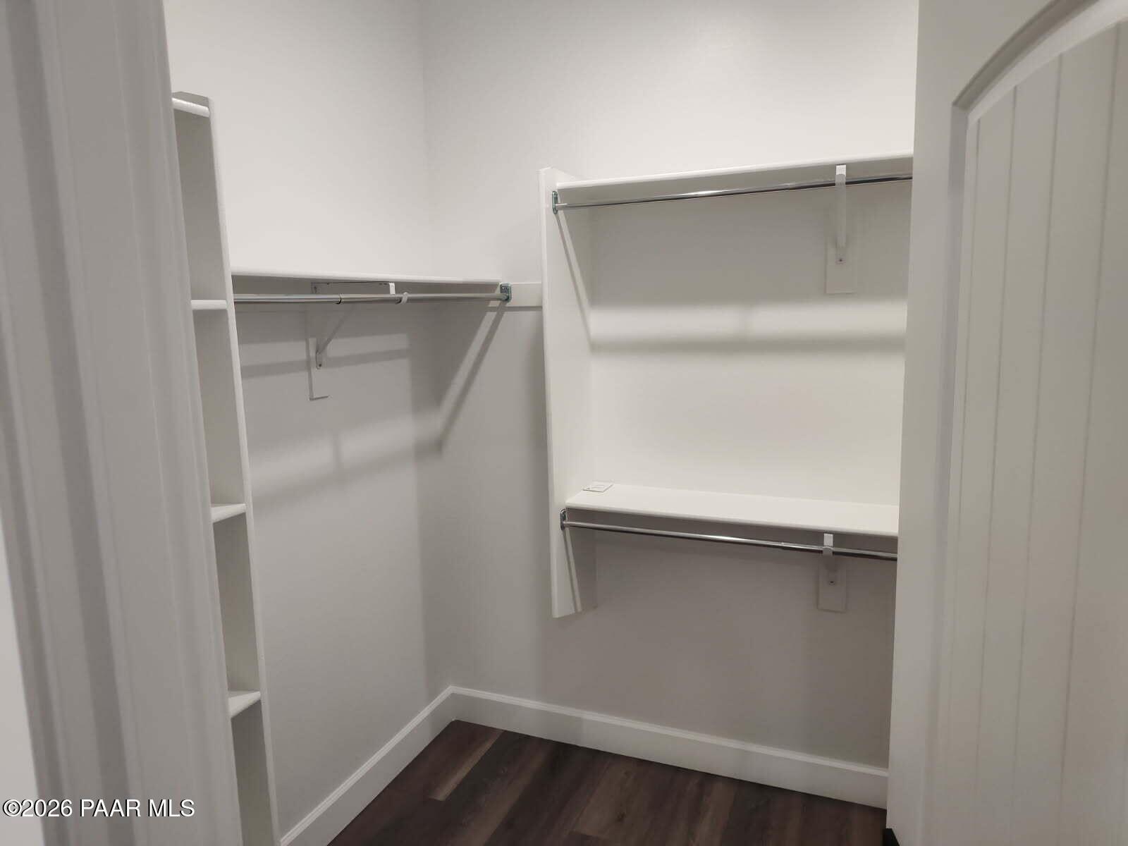Spacious walk-in closet with white shelving, double hanging rods, and luxury vinyl plank flooring in Davidson Homes The Harmony C, Prescott Valley, AZ