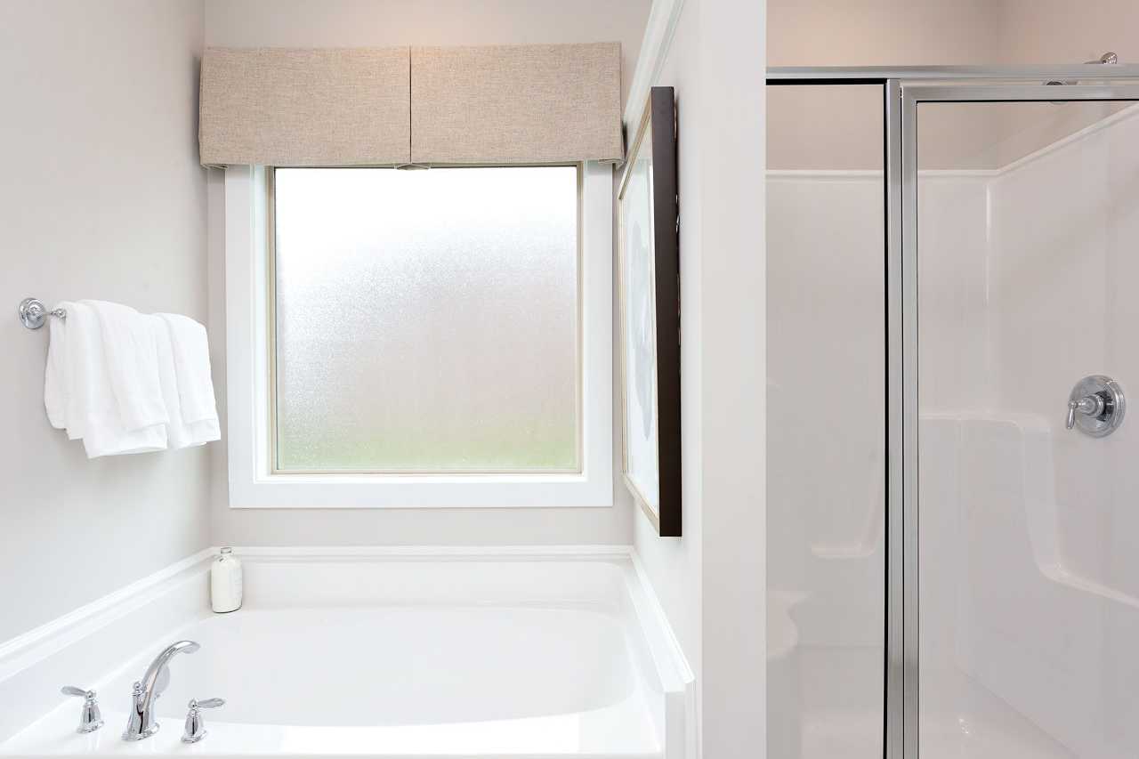 Spacious master bathroom in The Rockford Davidson Homes design featuring soaking tub, walk-in glass shower, frosted window