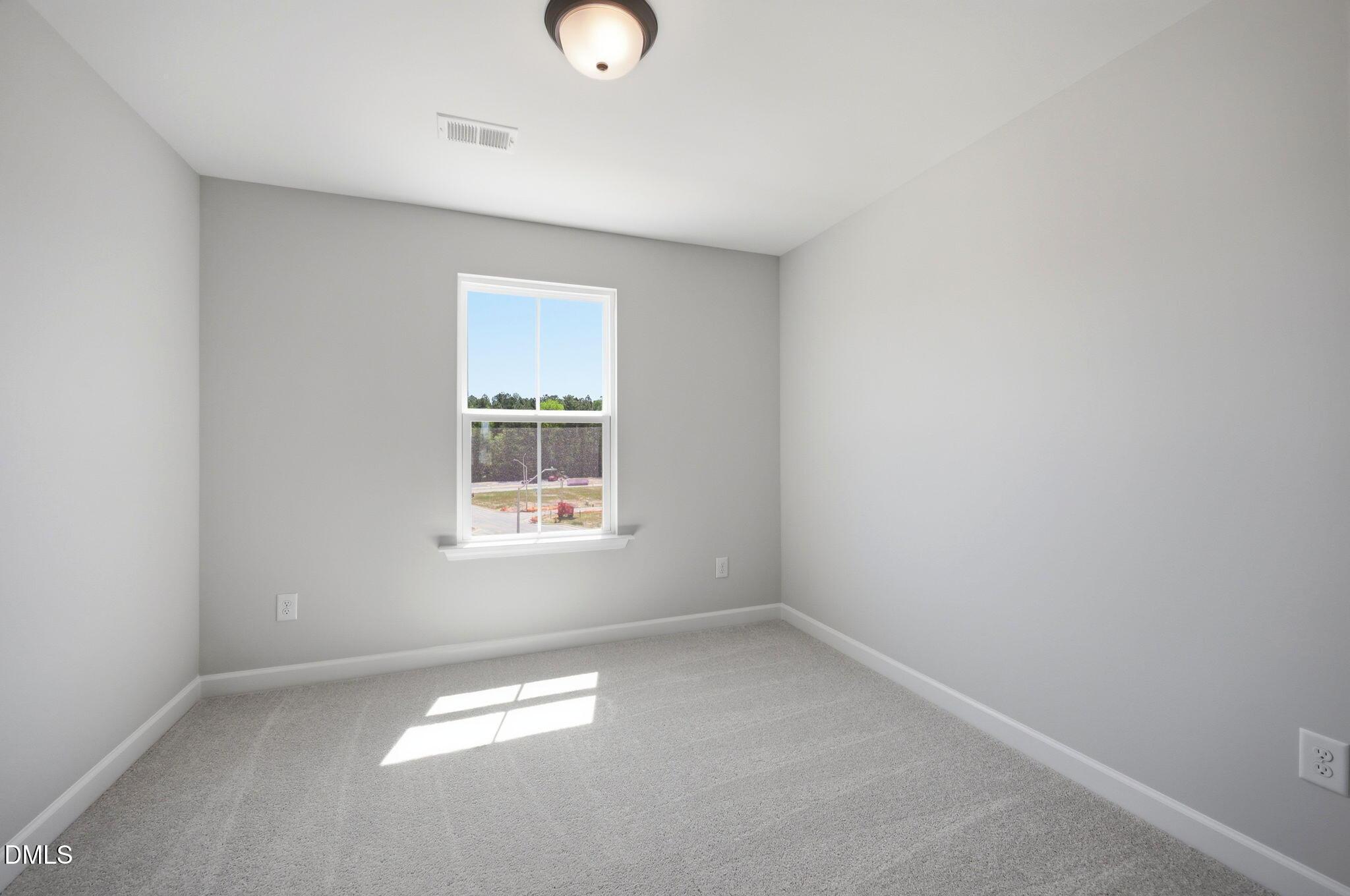 Bright, neutral bedroom with plush carpeting in The Avery floor plan at Forestville Yard Townhomes in Knightdale, NC.