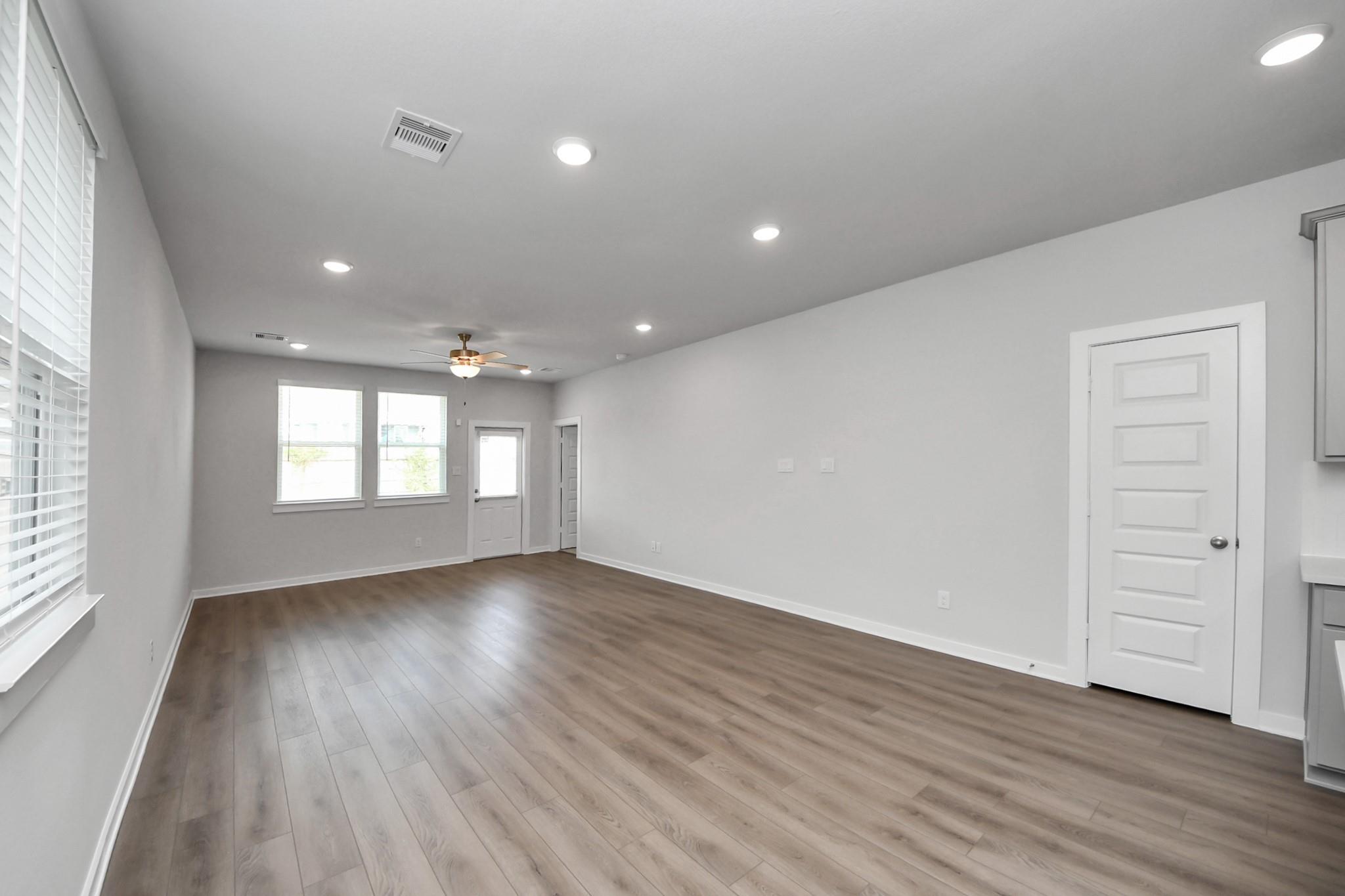 Open-concept living area with wood-look flooring and recessed lighting in Davidson Homes' The Frio F, Robins Landing, Houston