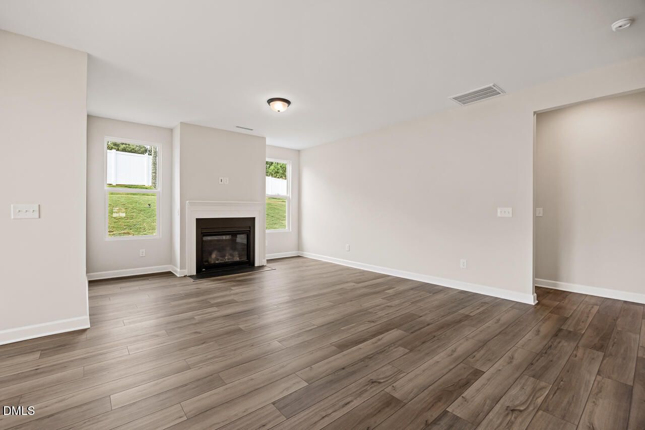 Spacious living room with fireplace and wood-style flooring in The Ash C floor plan at Woodland Crossing, Zebulon, NC.