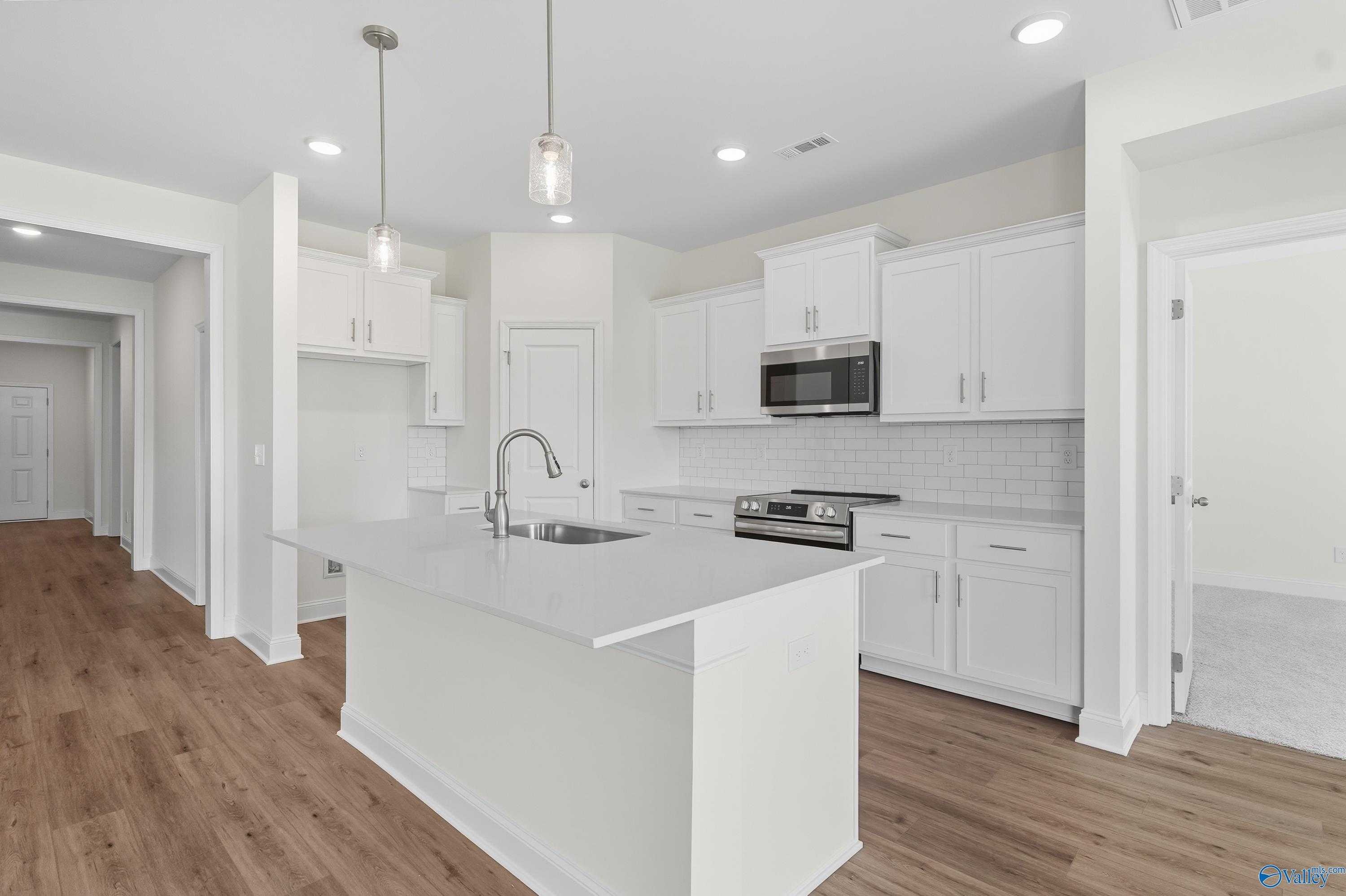 Modern white kitchen island with stainless appliances and open layout in Davidson Homes The Everett, Meridianville, Alabama