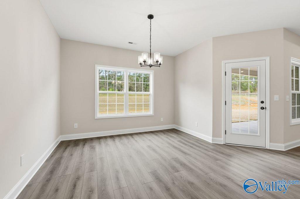 Spacious dining room with chandelier, large windows overlooking trees, and patio door in Davidson Homes Rockford B, Hartselle, Alabama