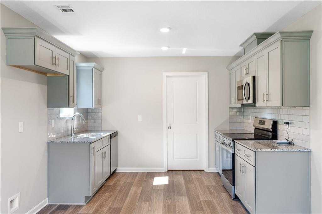 Modern kitchen featuring gray and white cabinets, stainless steel appliances, subway tile backsplash in The Washington floor plan, Phenix City, AL