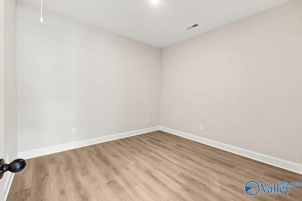 Bright bedroom with neutral walls and wood-style flooring in The Camilla C floor plan at The Retreat at Cain Park, Hartselle.