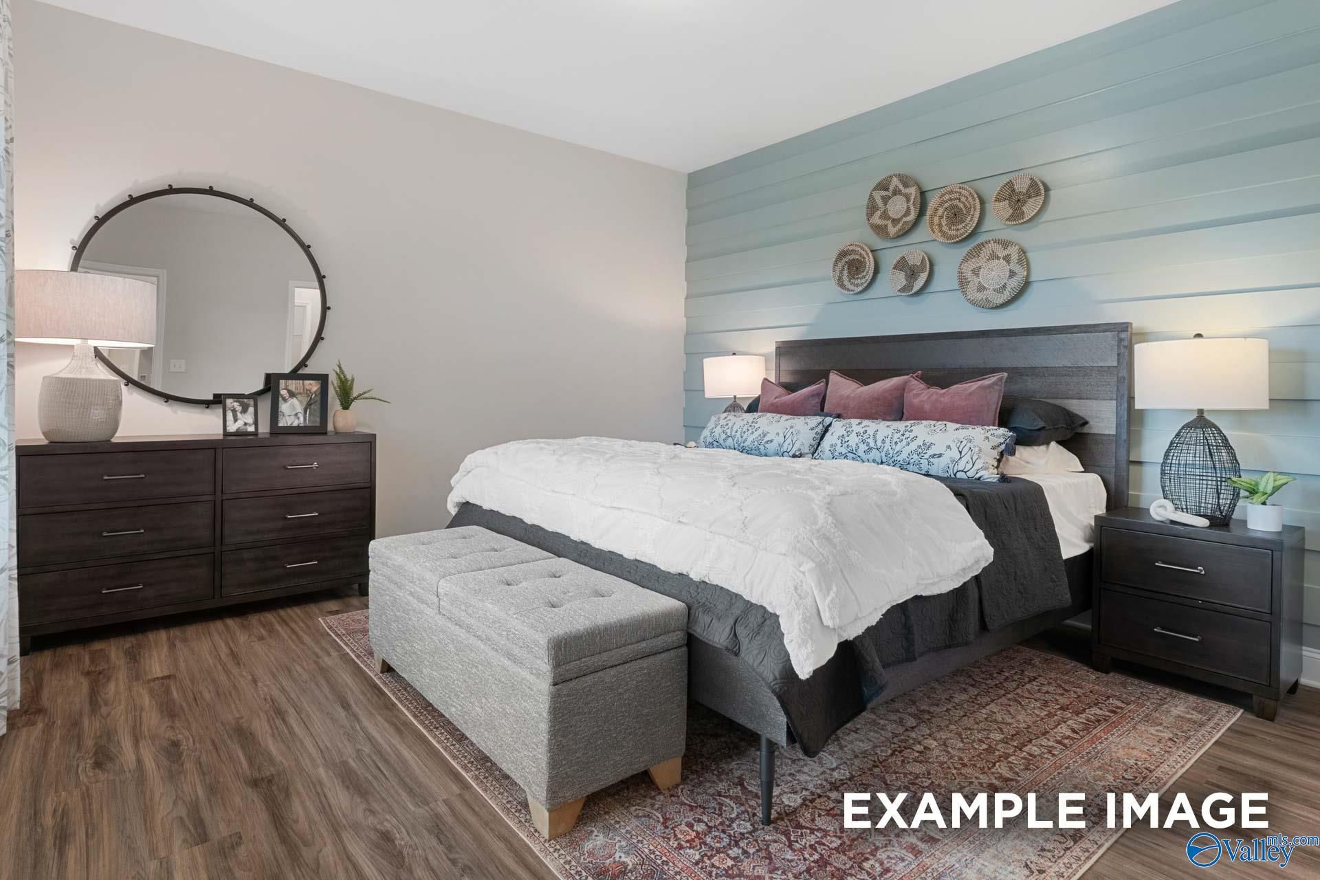 Cozy master bedroom with shiplap accent wall, dark wood furniture, and hardwood floors in Davidson Homes The Camilla C, Hartselle