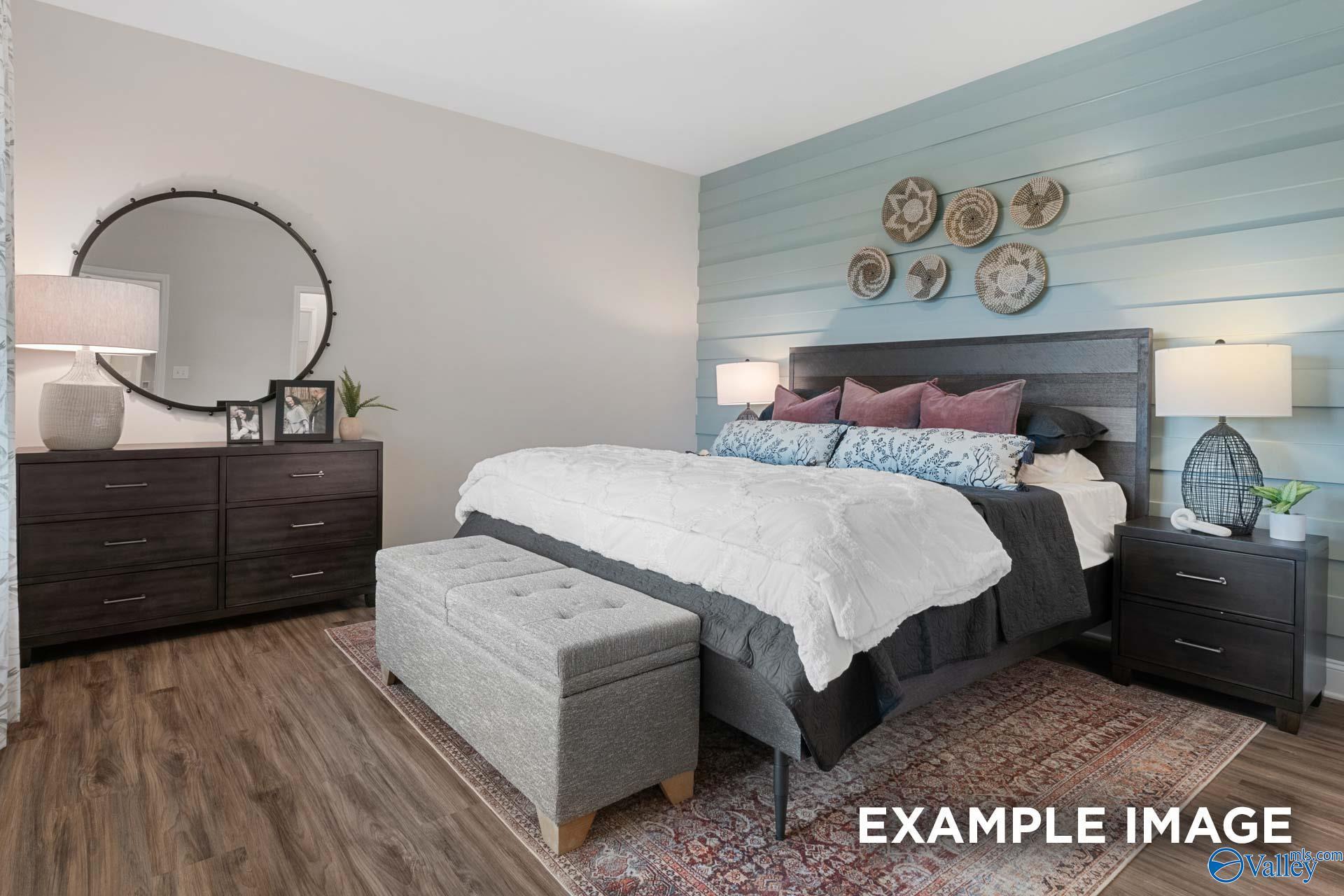 Cozy master bedroom with shiplap accent wall, dark wood furniture, and hardwood floors in Davidson Homes The Camilla C, Hartselle