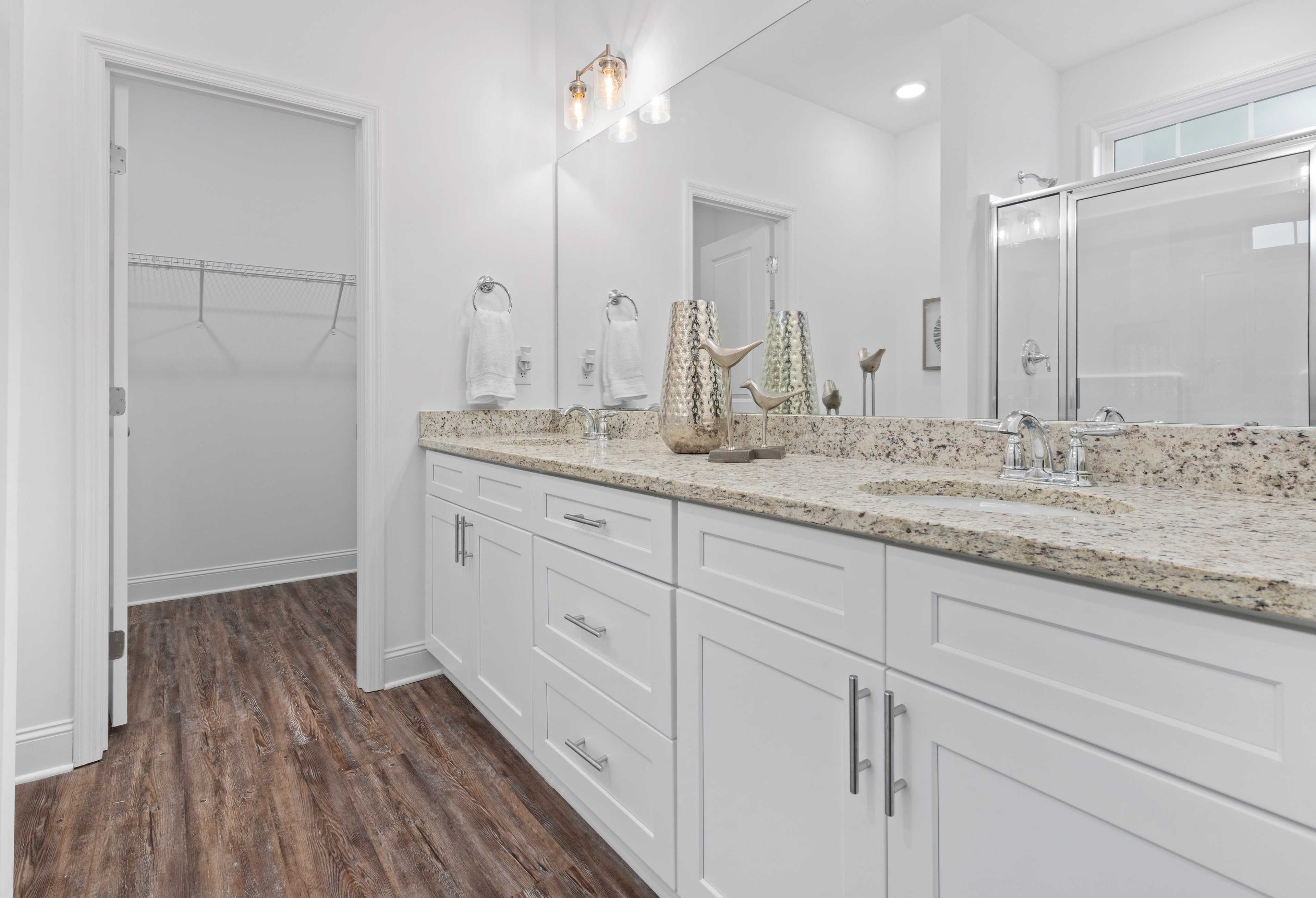 Spacious master bathroom in The Cumberland with double vanity, quartz counters, white cabinets, glass shower, walk-in closet