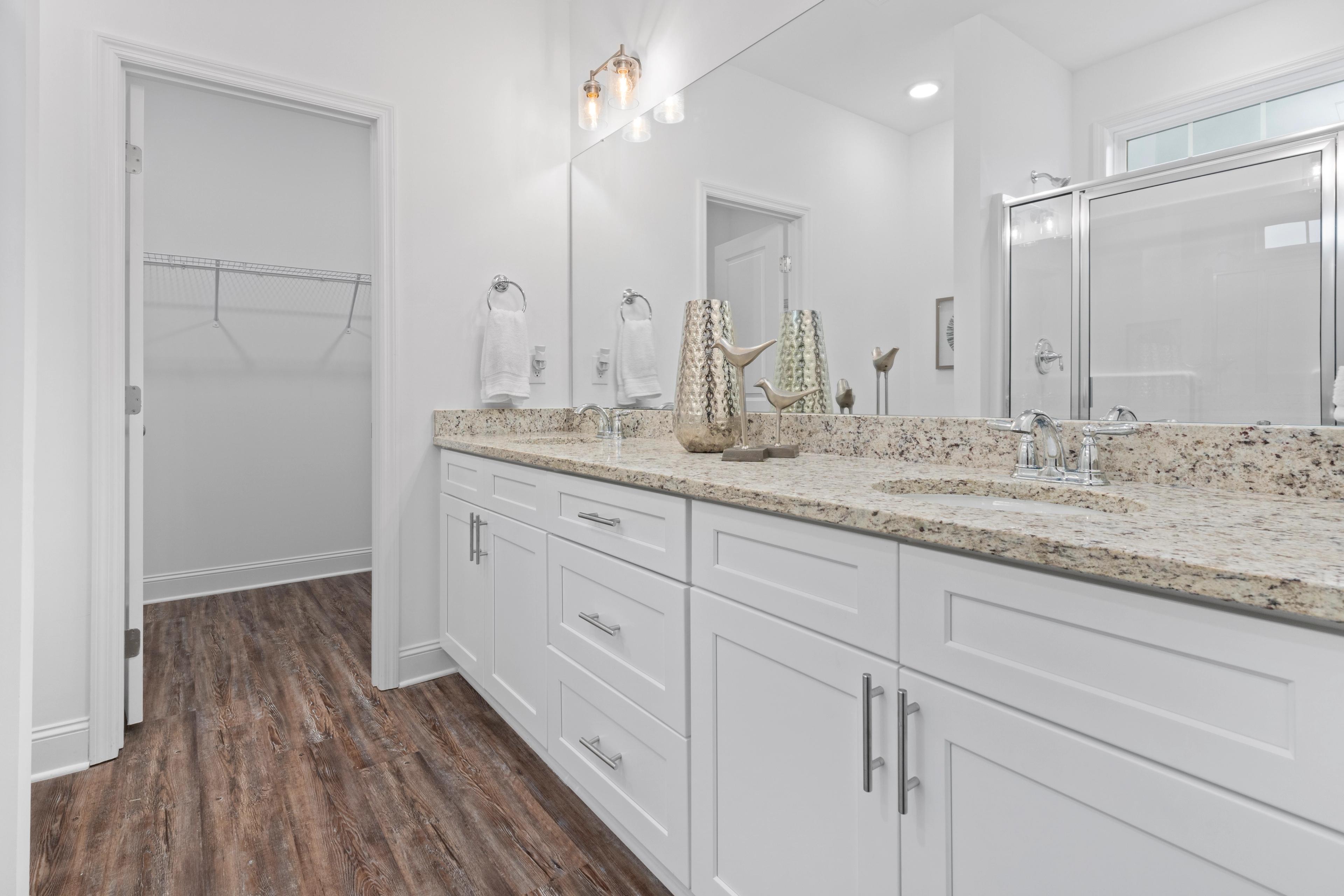 Spacious master bathroom in The Cumberland B with double vanity, quartz countertop, glass shower, and walk-in closet