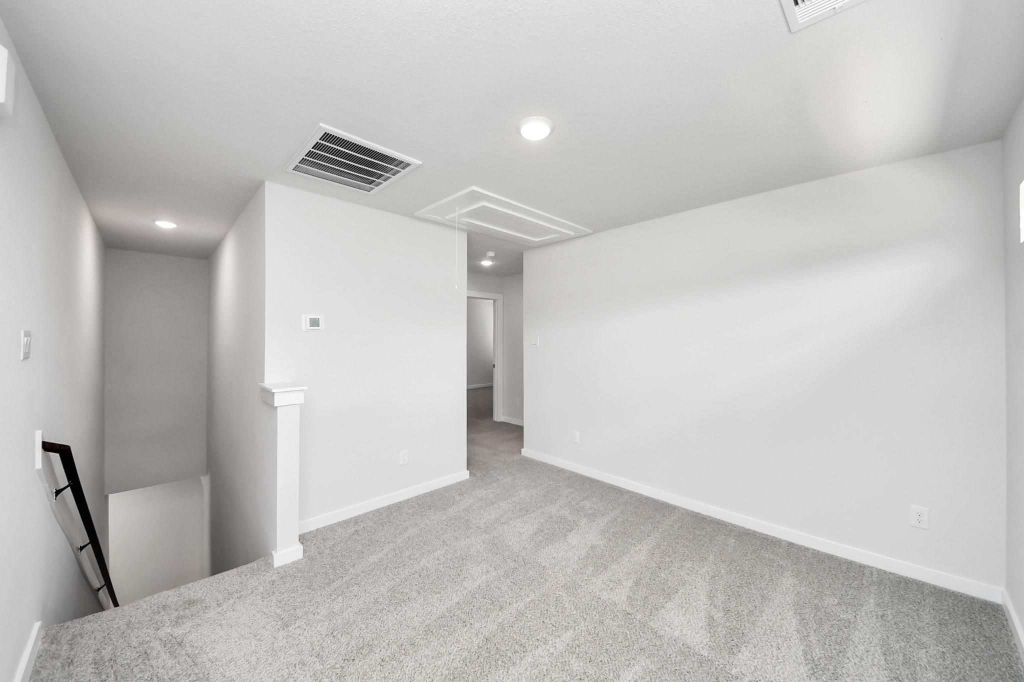 Bright upstairs loft area with plush carpet in The Sabine E floor plan by Davidson Homes in Liberty Estates, Texas.