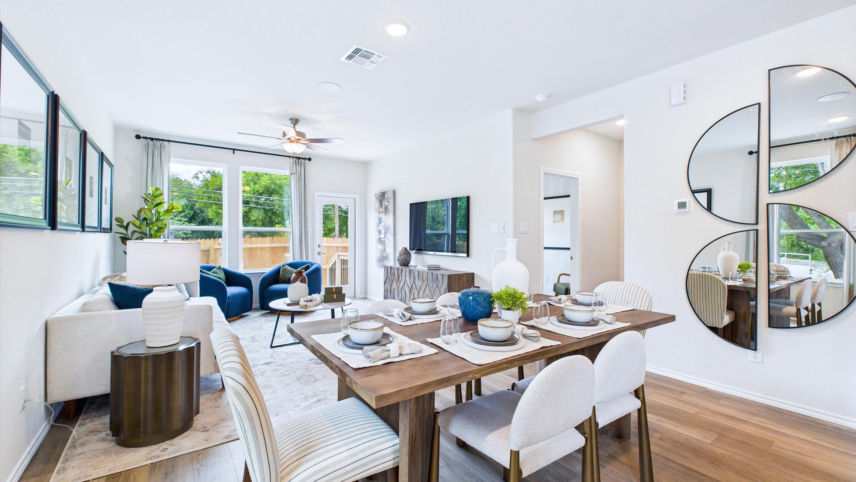 Open-concept living and dining area in Cedar Heights San Antonio home with white sofa, wooden table, plants, and hardwood floors