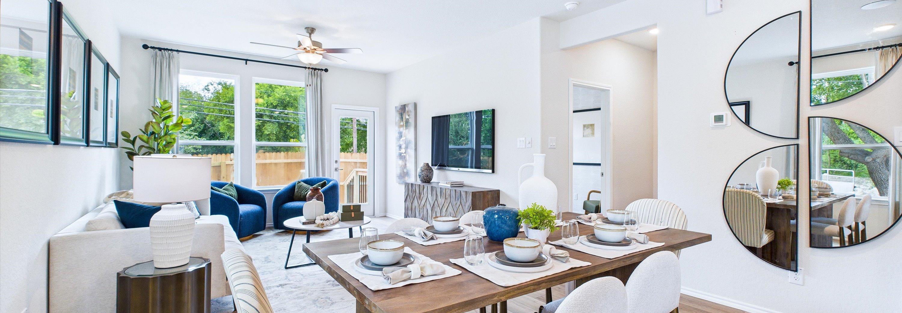 Open-concept living and dining area in Cedar Heights San Antonio home with white sofa, wooden table, plants, and hardwood floors