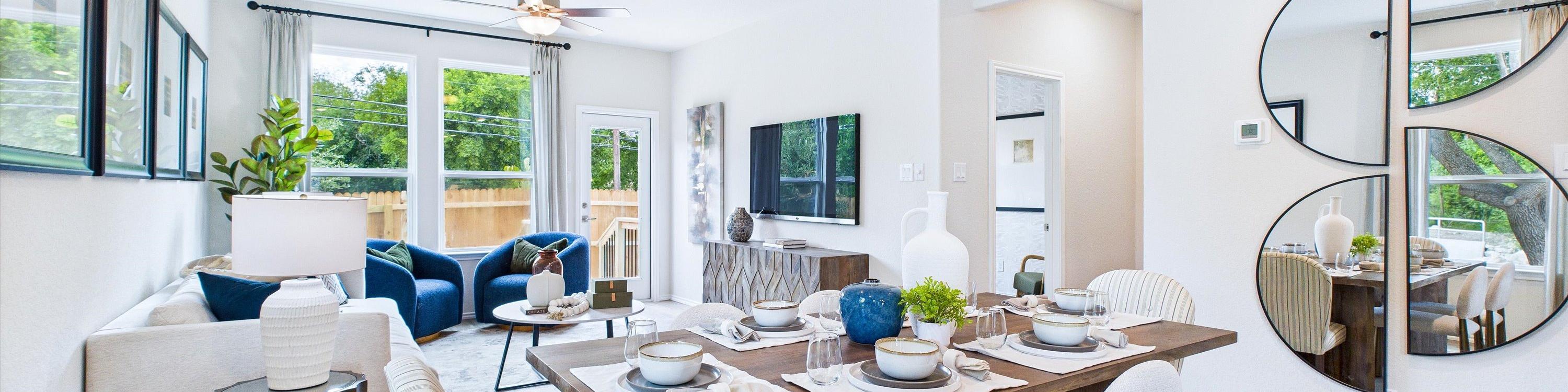 Open-concept living and dining area in Cedar Heights San Antonio home with white sofa, wooden table, plants, and hardwood floors