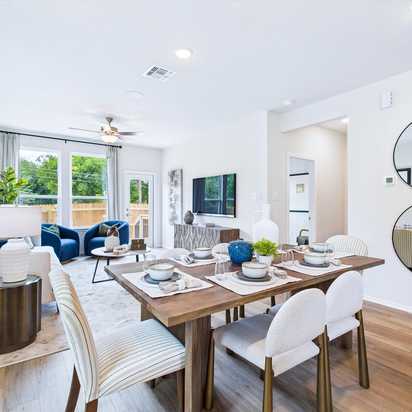 Open-concept living and dining area in Cedar Heights San Antonio home with white sofa, wooden table, plants, and hardwood floors