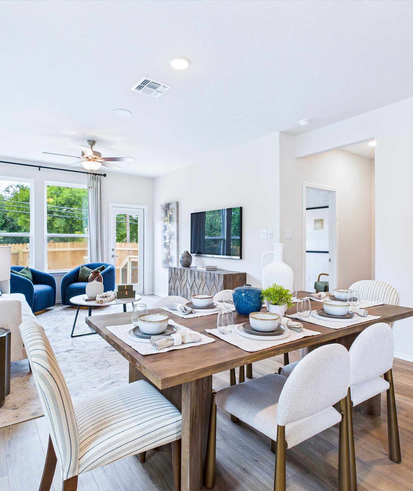 Open-concept living and dining area in Cedar Heights San Antonio home with white sofa, wooden table, plants, and hardwood floors