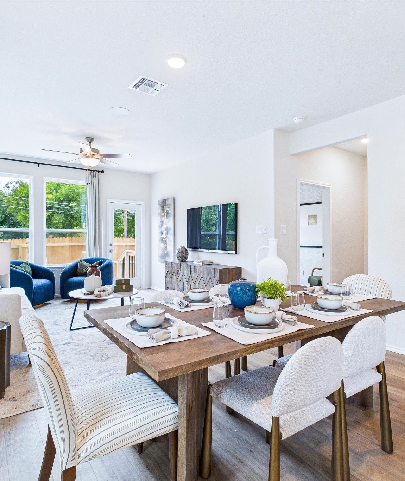 Open-concept living and dining area in Cedar Heights San Antonio home with white sofa, wooden table, plants, and hardwood floors