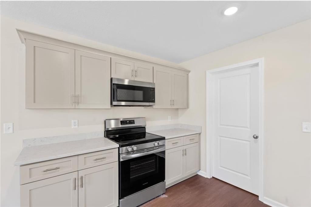Modern kitchen with stainless steel appliances, white quartz counters, and shaker cabinets in Davidson Homes The Washington, Phenix City, AL
