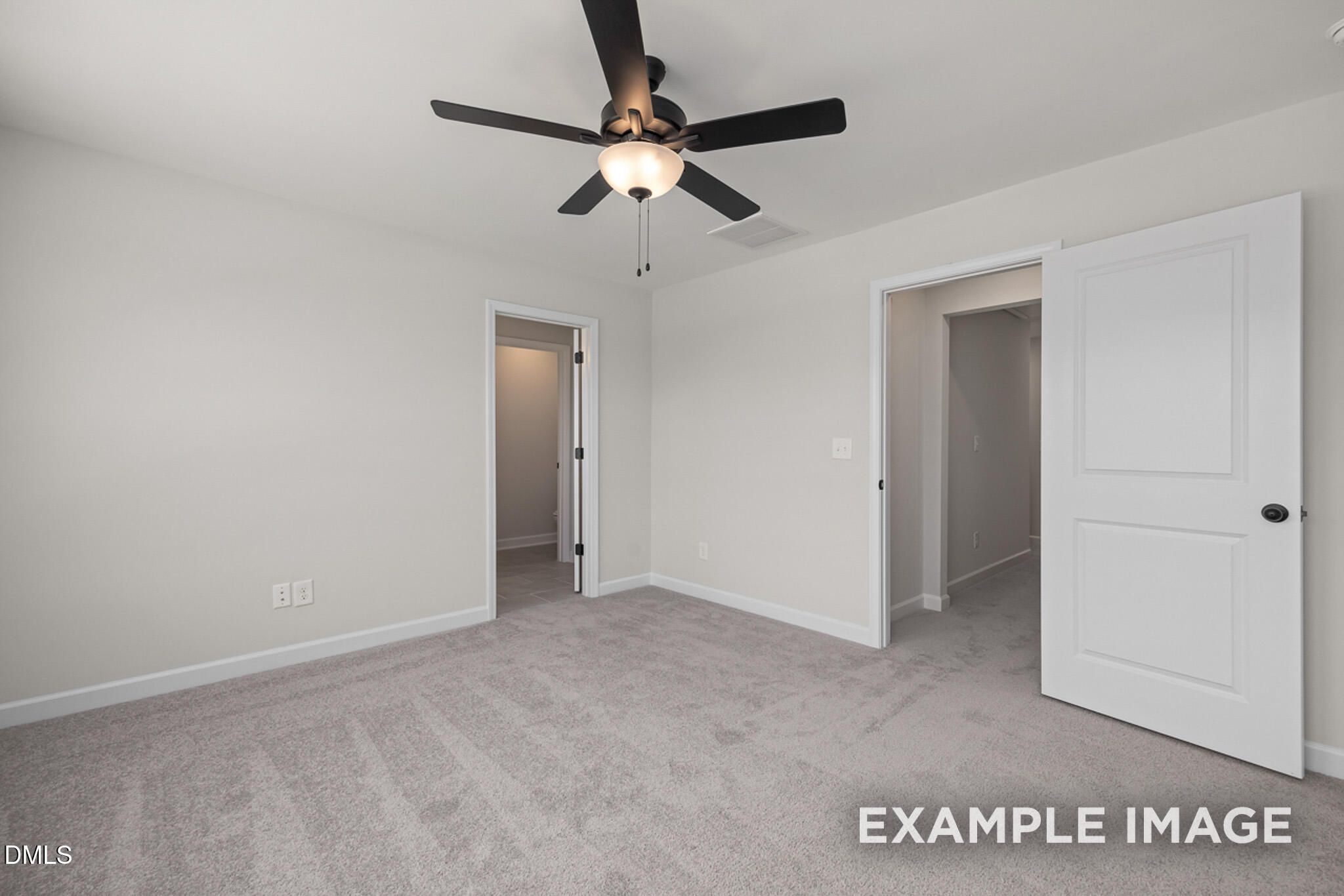 Spacious bedroom with gray carpeting, ceiling fan, and doorways in The Mitchell floor plan at Camden Park, Knightdale, NC.