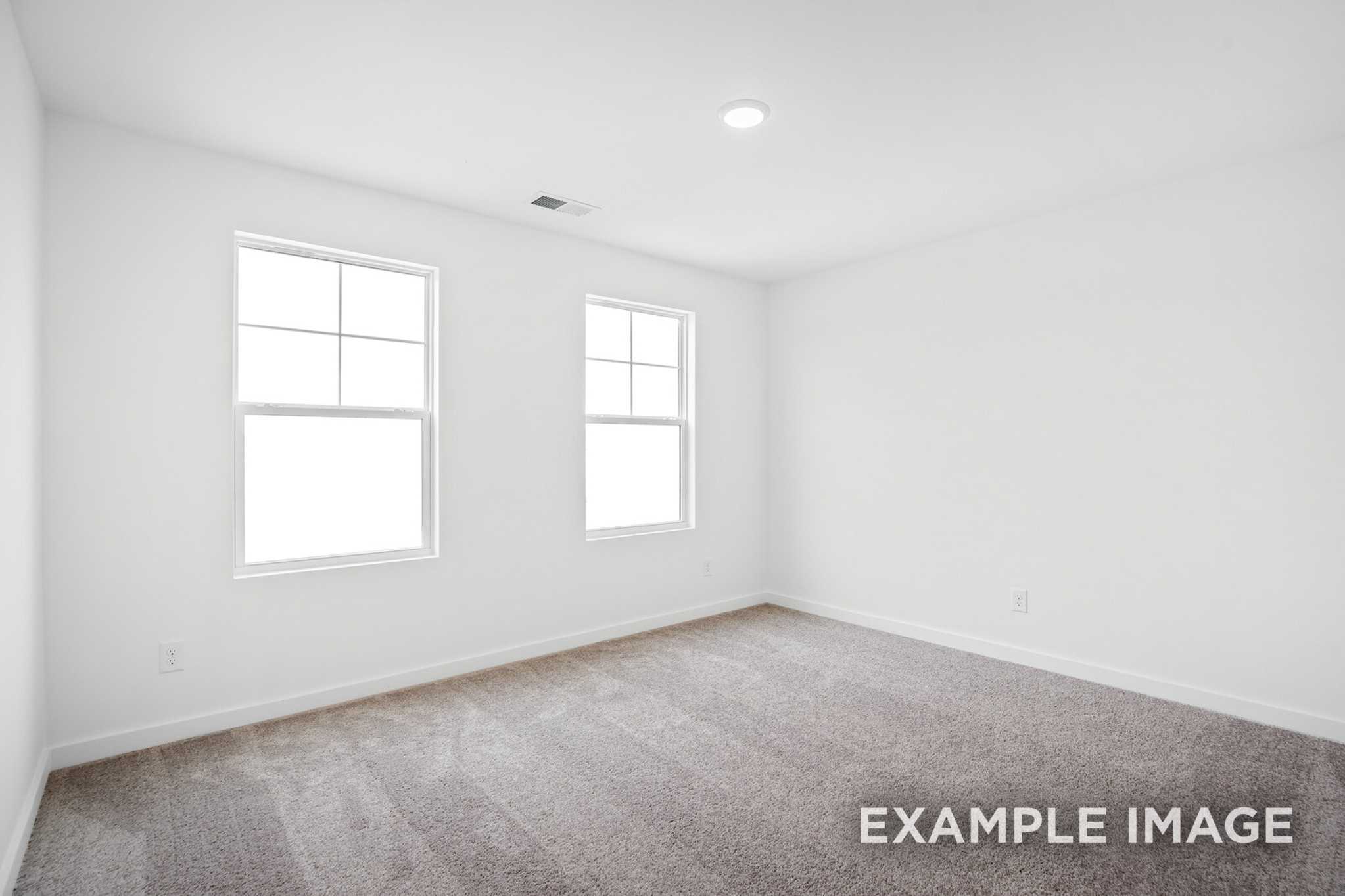 Spacious upper-floor bedroom in The Grayson C with white walls, double windows, carpeted floor