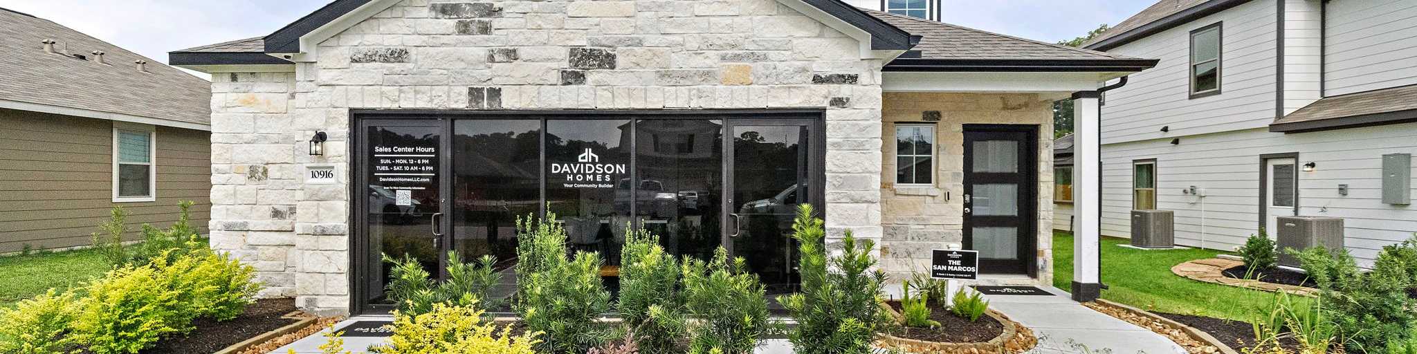 Modern kitchen at Liberty Estates in Cleveland Texas by Davidson Homes featuring white cabinets granite island red bar stools and stainless appliances