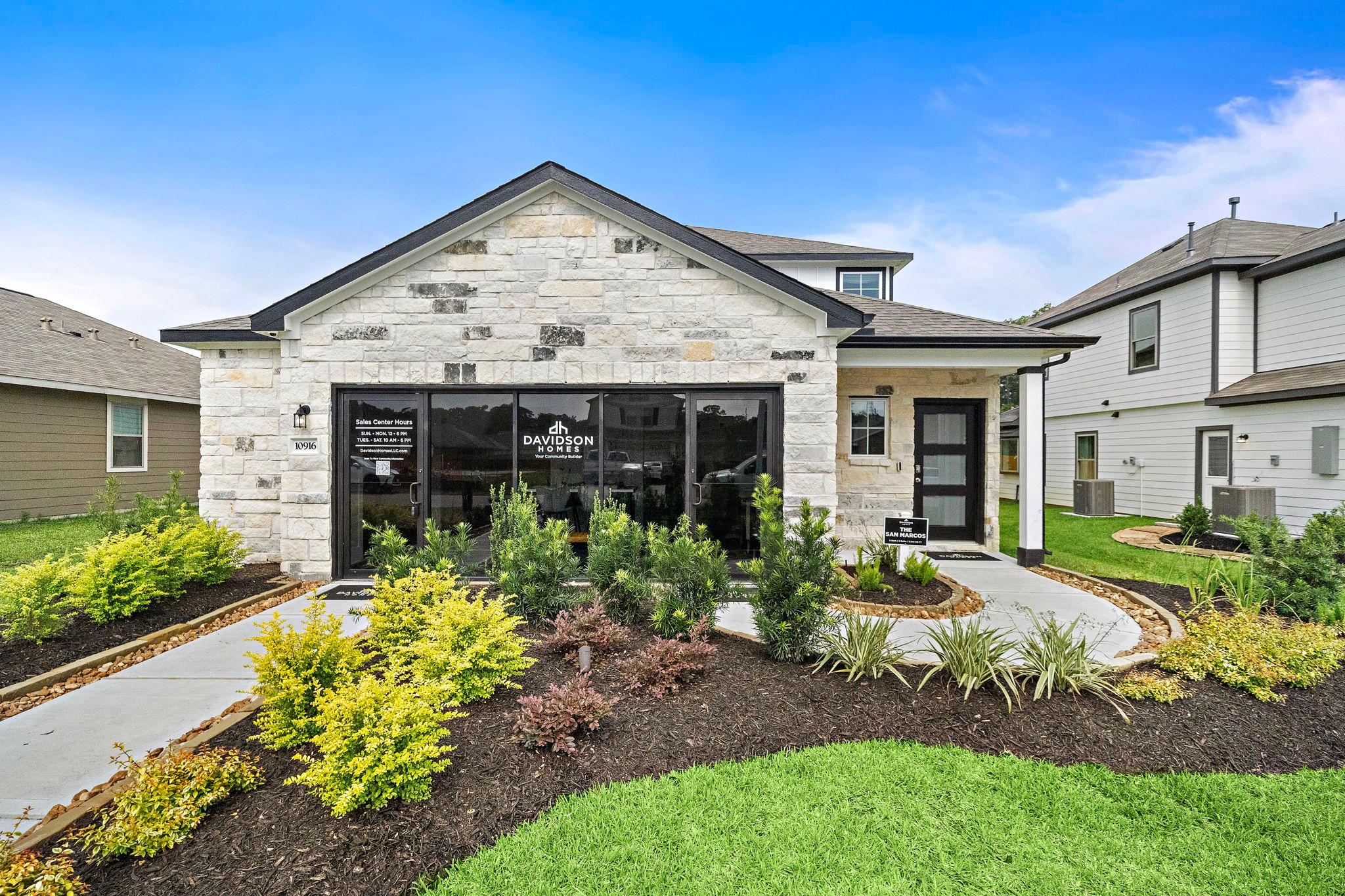 Modern kitchen at Liberty Estates in Cleveland Texas by Davidson Homes featuring white cabinets granite island red bar stools and stainless appliances
