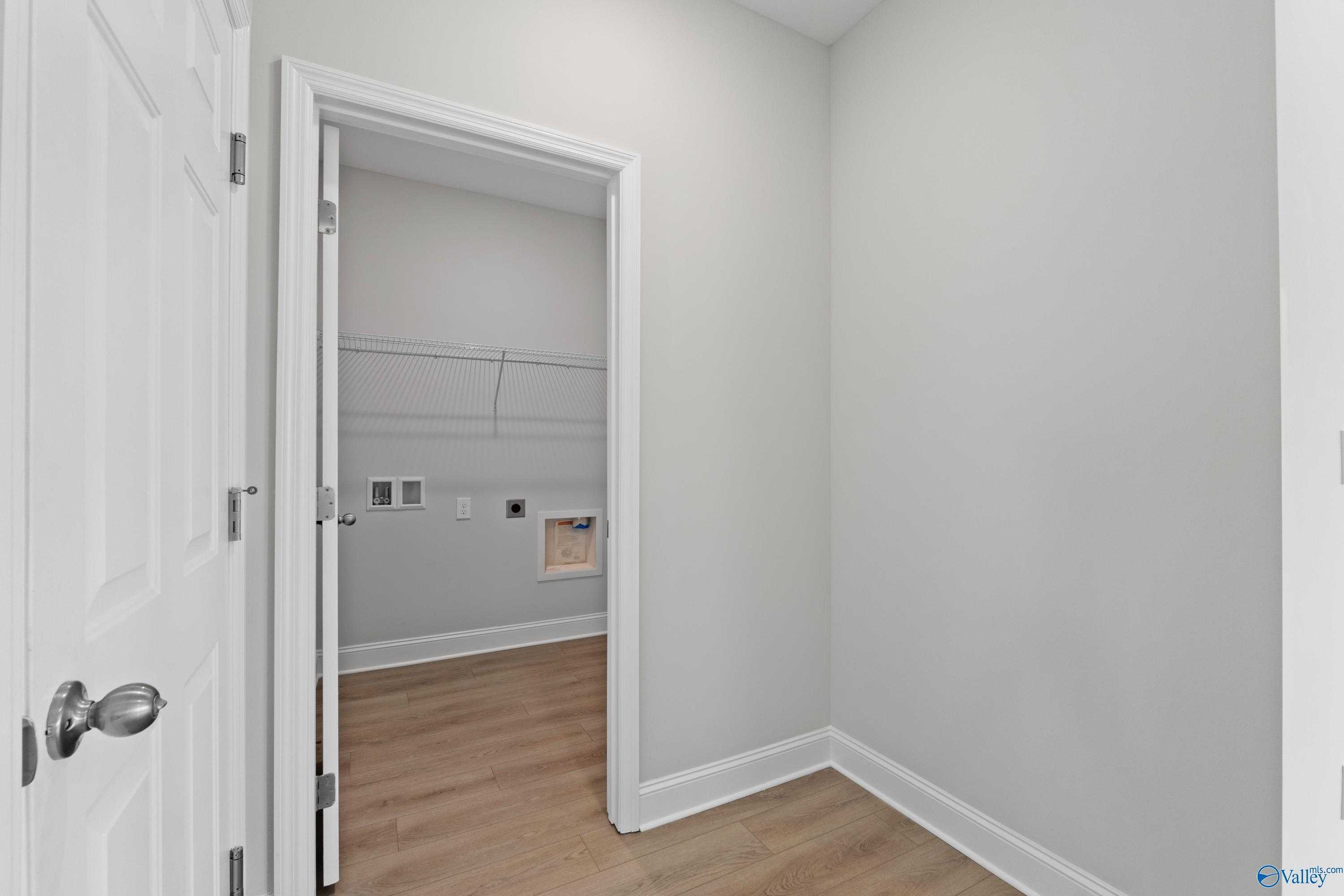 Laundry closet featuring hanging rod, washer-dryer outlets, gray walls, and laminate flooring in Davidson Homes The Franklin C, Harvest AL