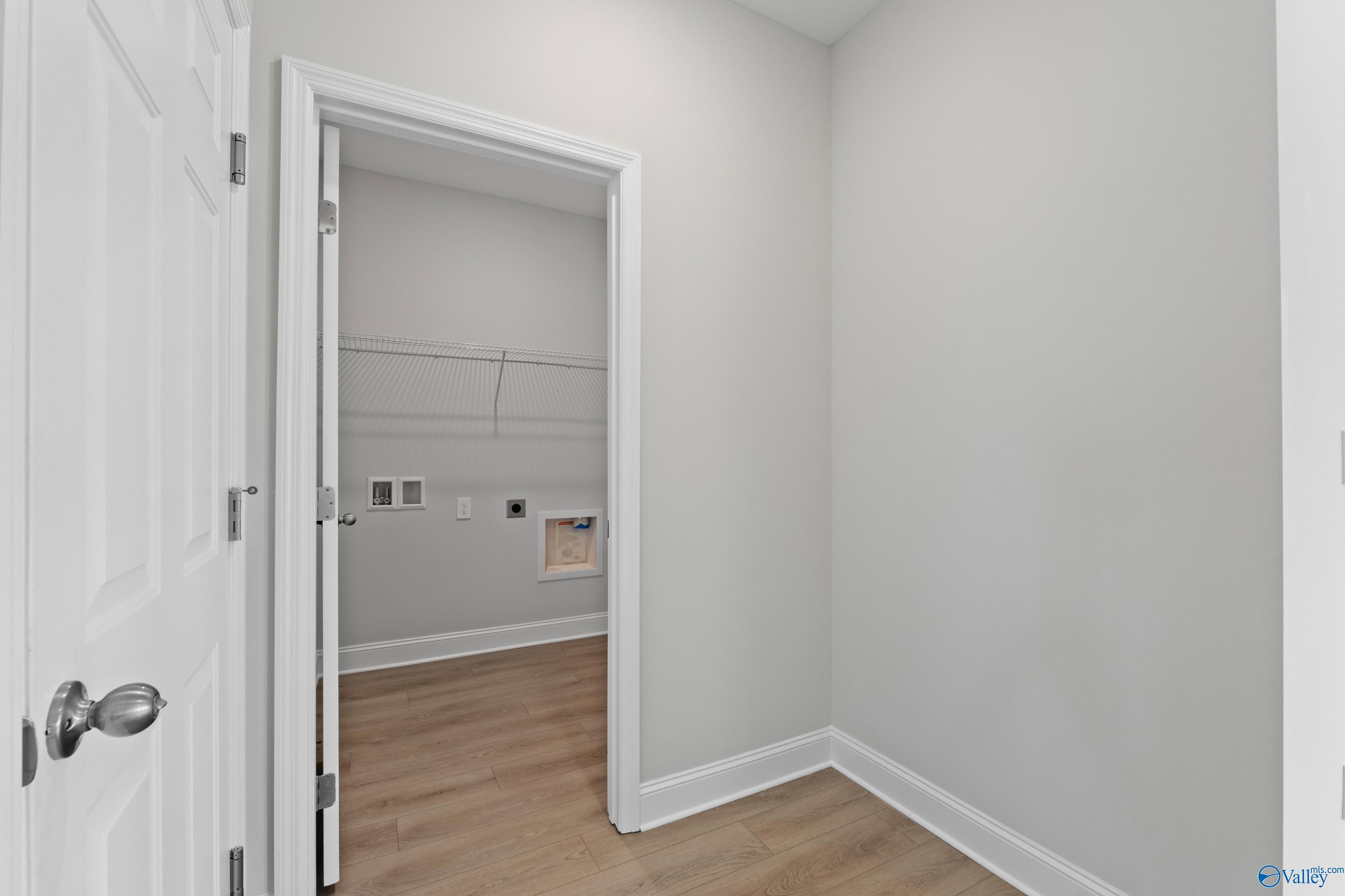 Laundry closet featuring hanging rod, washer-dryer outlets, gray walls, and laminate flooring in Davidson Homes The Franklin C, Harvest AL