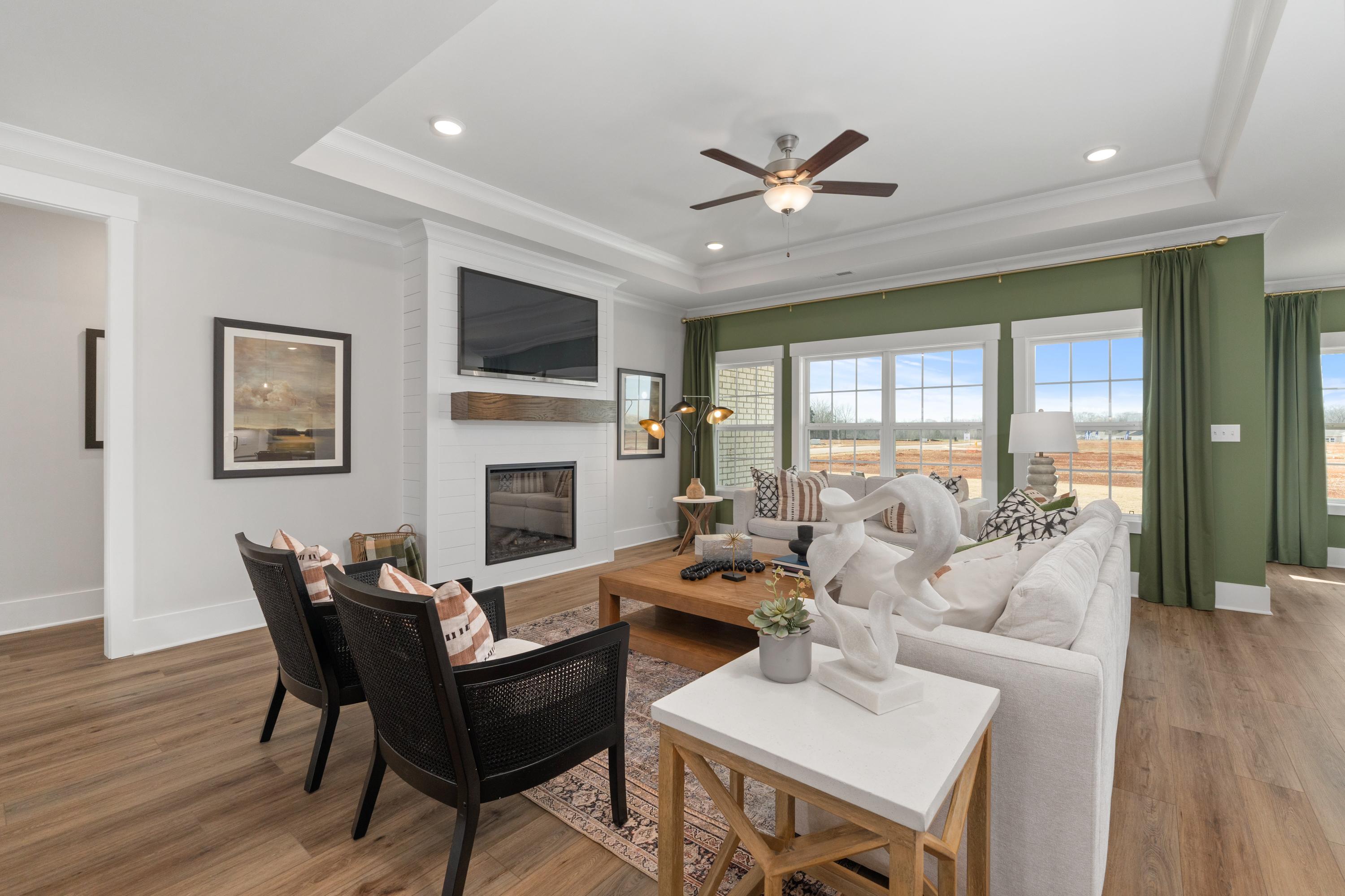 Cozy open-concept living room at Briercreek in Meridianville Alabama with white sofa fireplace hardwood floors and large windows