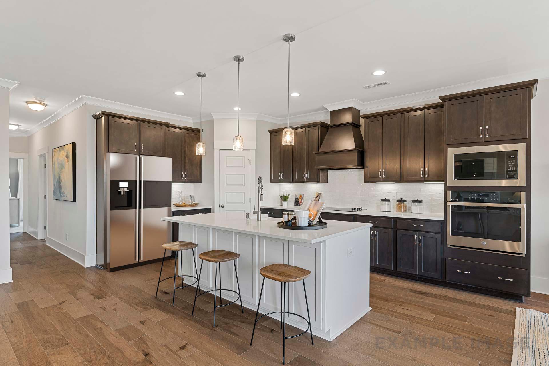 Modern kitchen in The Rockford home with white quartz island, dark wood cabinets, stainless steel appliances, and hardwood floors