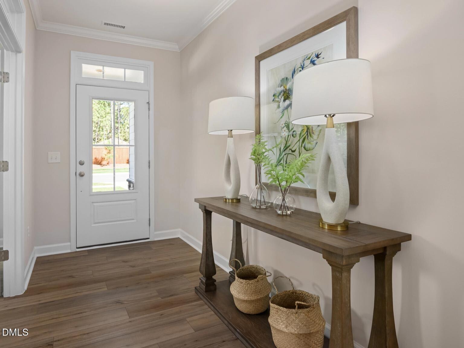 Elegant entryway with wooden console table, white lamps, greenery vase, and framed artwork in Davidson Homes The Hickory II D, Wake Forest, NC