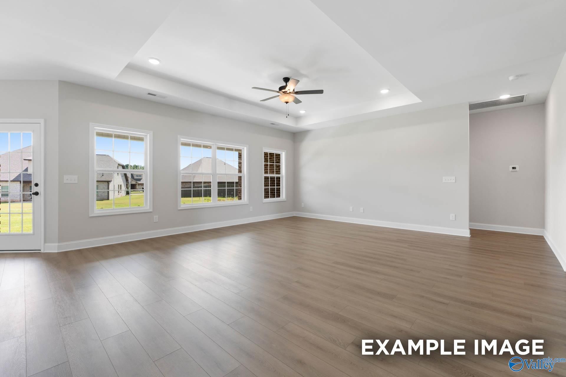Spacious open living room with hardwood floors, large windows to yard, and ceiling fan in Davidson Homes The Rockford, Decatur, Alabama
